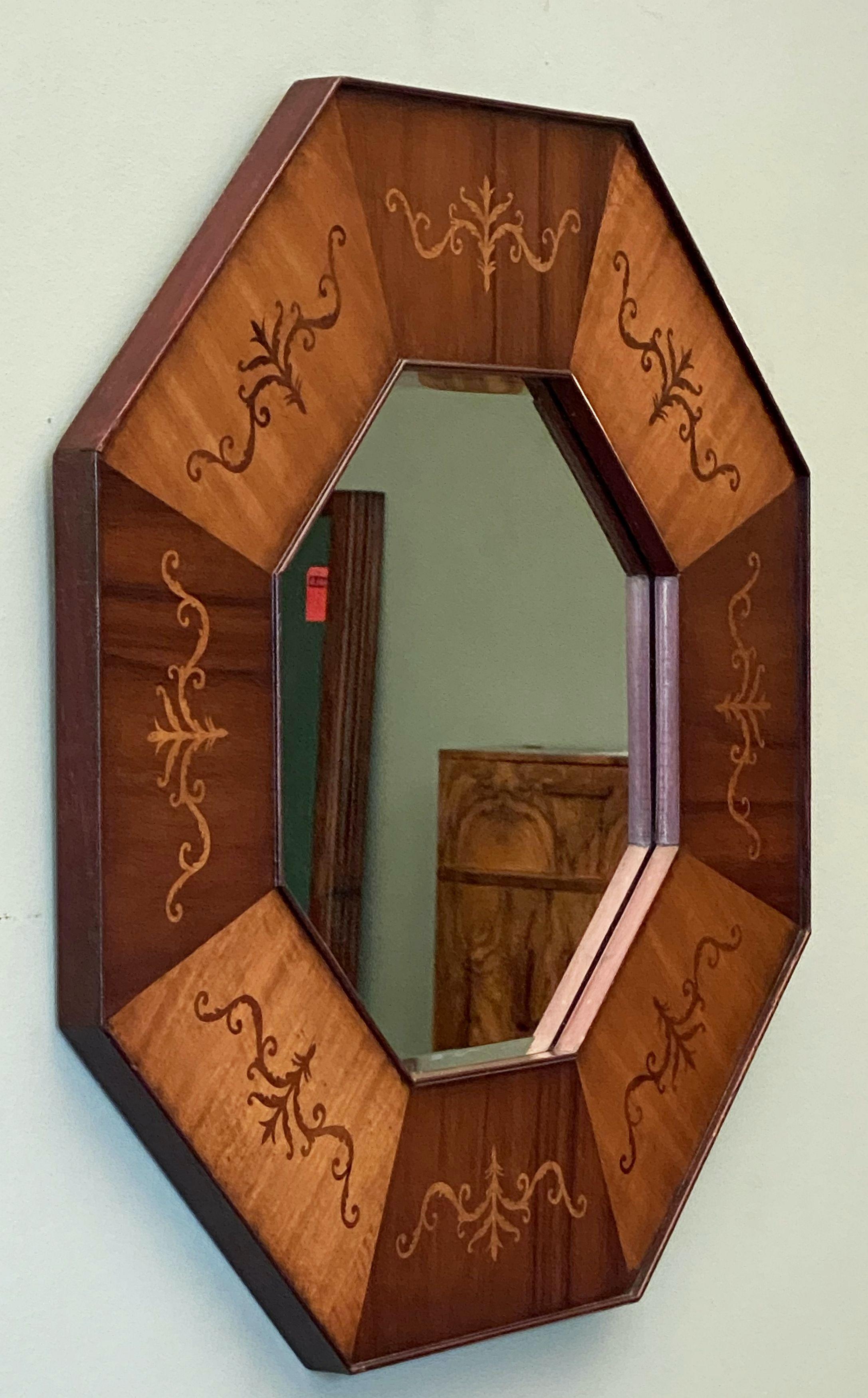 A fine English octagonal wall mirror featuring an eight-sided moulded panel frame of inlaid mahogany, with a scrollwork design to each panel, surrounding a beveled mirrored glass center.

Measure: Diameter is 26 1/2 inches.