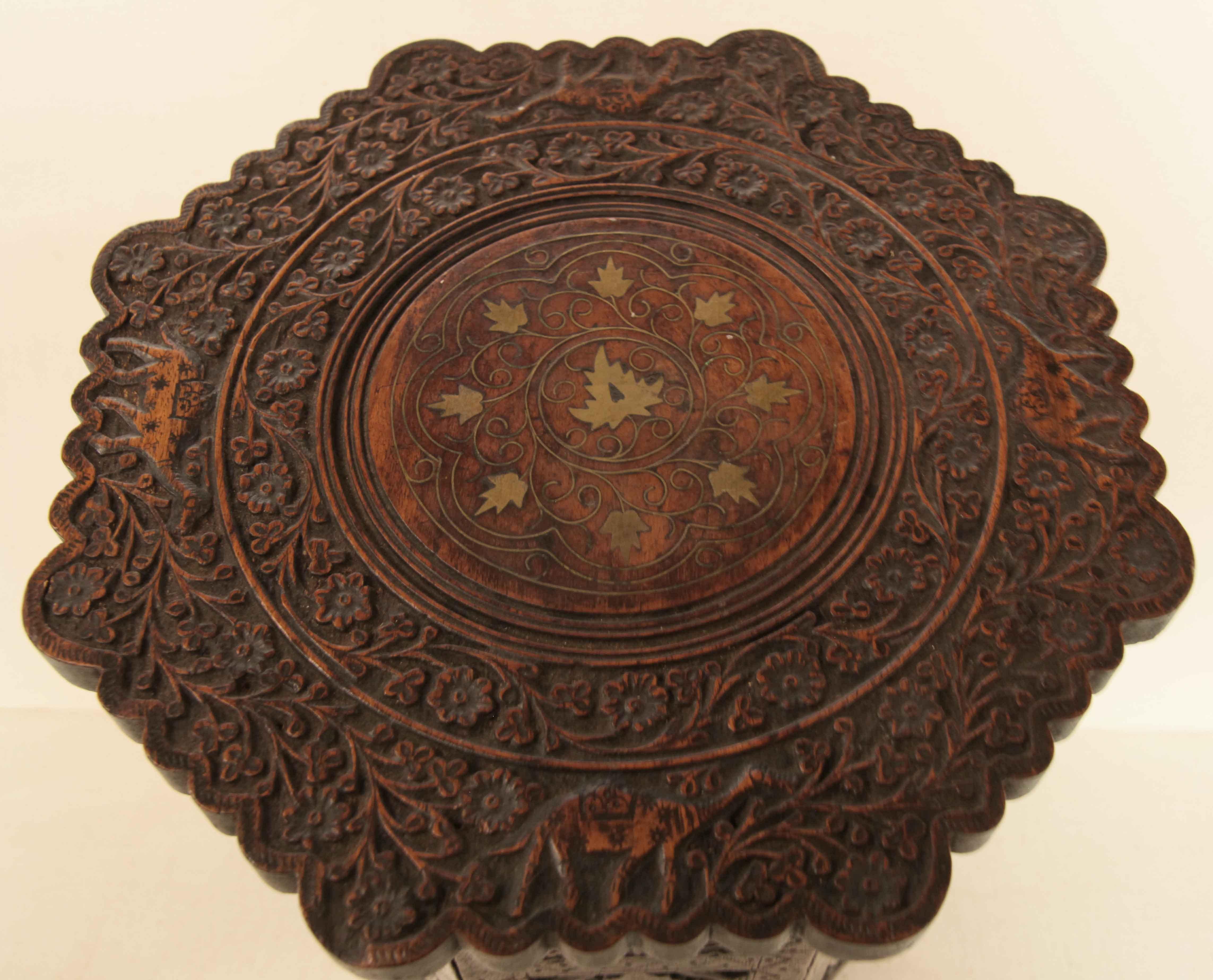 Octagonal Moraccan carved side table, the top has a scalloped shaped edge with a border of flowers and scrolling foliage along with camels, the center features a circle of inlaid brass flowers and arabesques. .  The hinged base has eight identical