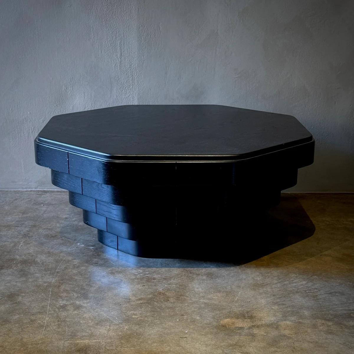 This striking octagonal coffee table, inspired by the designs of Jules Wabbes, features an ebonized finish that emphasizes its geometric form and contemporary elegance. The table's faceted edges and substantial size make it a dramatic centerpiece,
