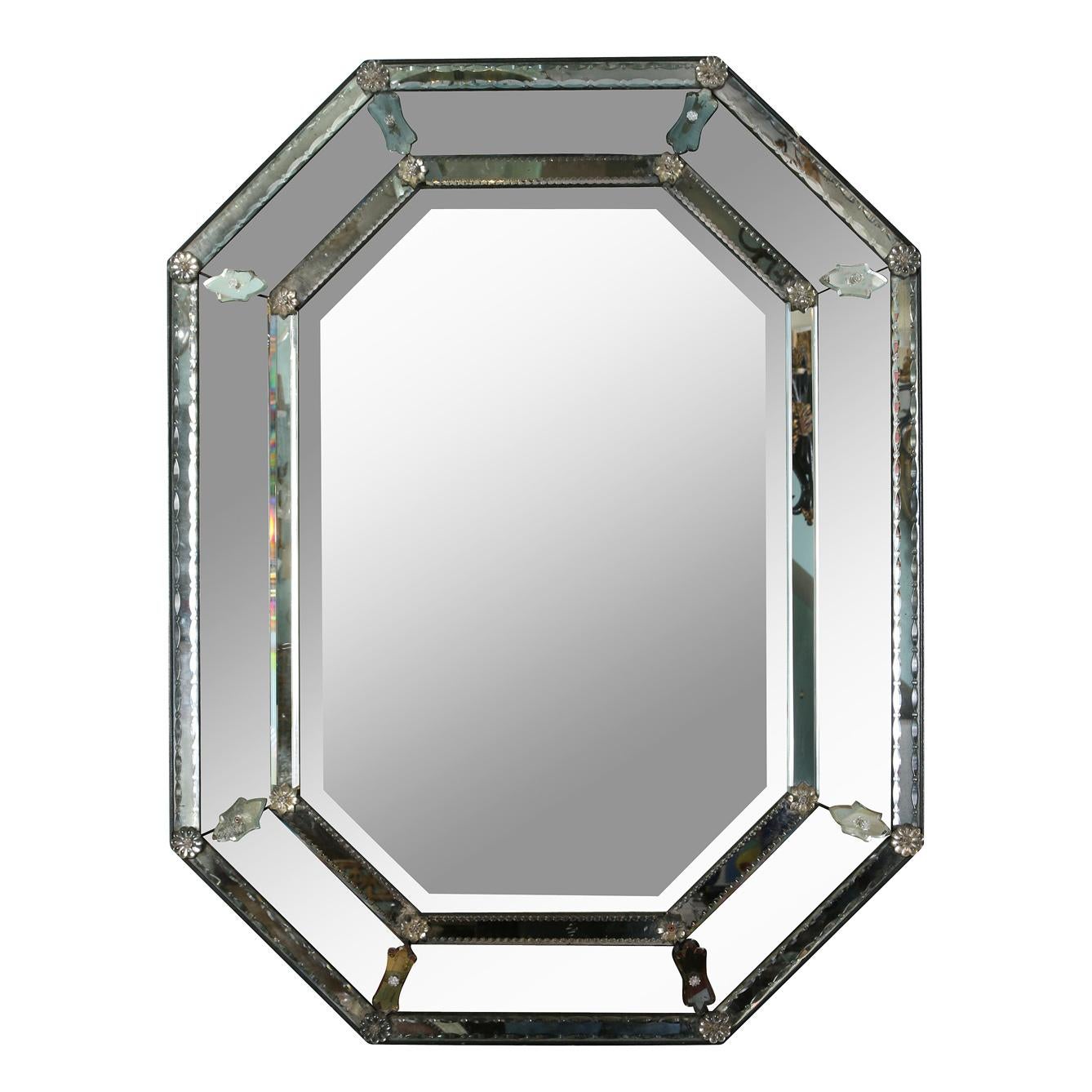 Un miroir vénitien octogonal à facettes vintage avec deux belles bandes de plaques de miroir détaillées qui scintillent avec un bord à motif complexe sur chaque bande.  Le double bandeau entoure des plaques miroirs en angle avec des détails