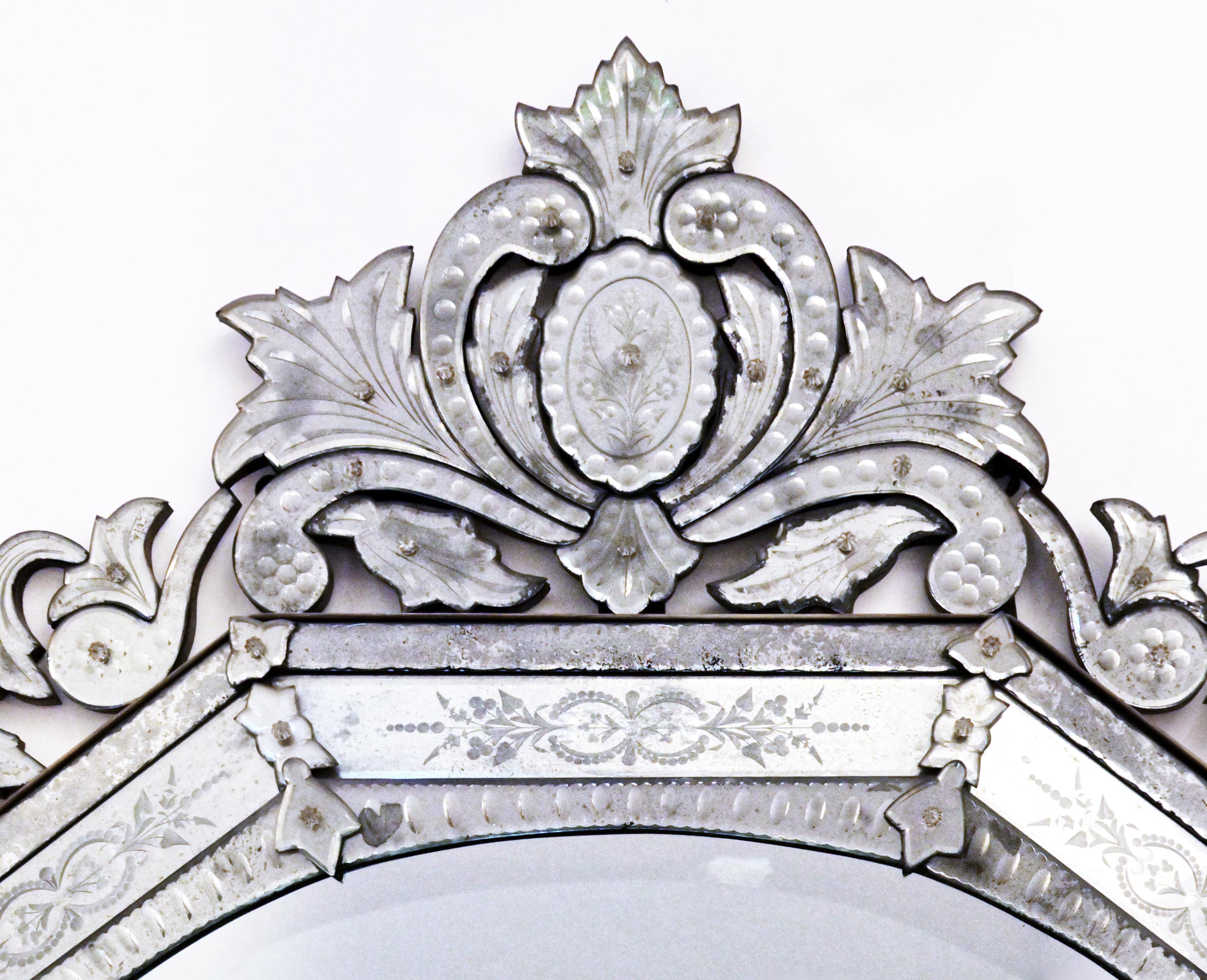 An octagonal horizontal Venetian mirror with bevelled center glass with notched edges the sections secured by glass rosettes and having leaf and floral motif carved decoration. The top surmounted by cartouche flanked by leaf shaped mirrored glass