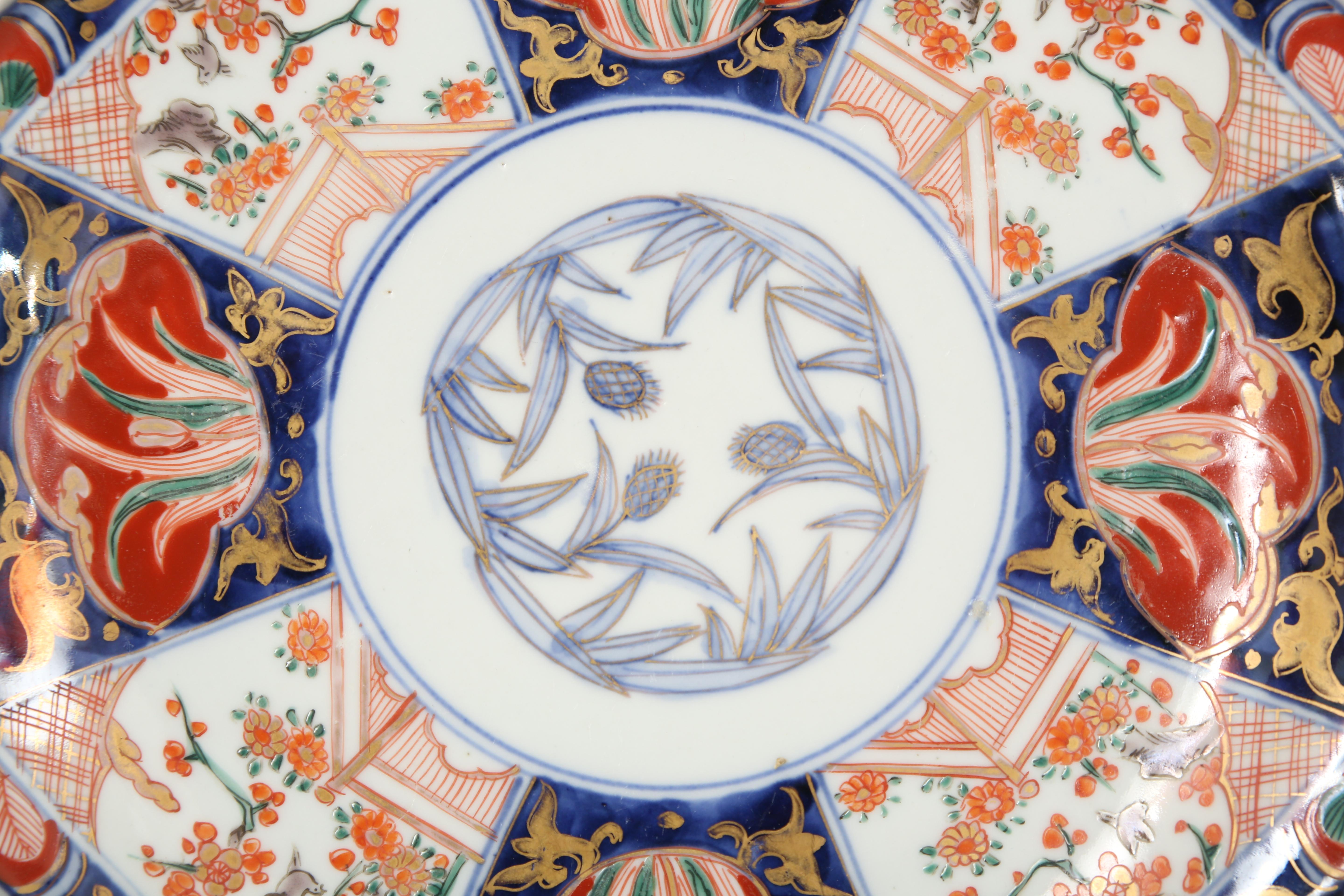 Imari octagonal porcelain plate hand decorated in underglaze blue and over painted in iron red, green and gold enamels. The center is surrounded by eight panels of alternating images. The reverse side has a decorated border in underglaze blue.