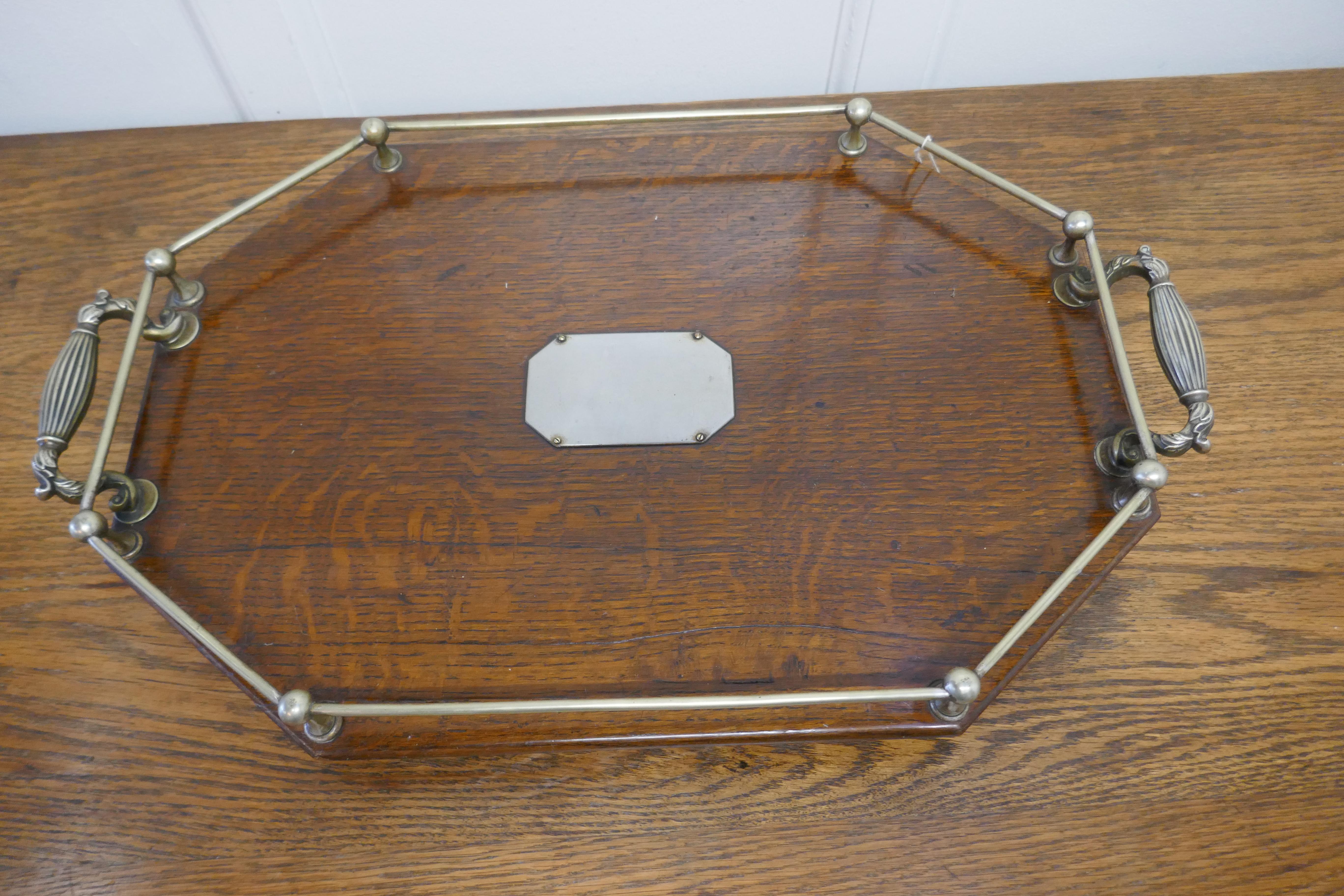 Octagonal oak and silver plated drinks tray 

A lovely traditional piece, the tray is made in polished oak with Silver plated detail. The tray has a gallery rail all of the way around, strong carrying handles with a presentation plaque (this is