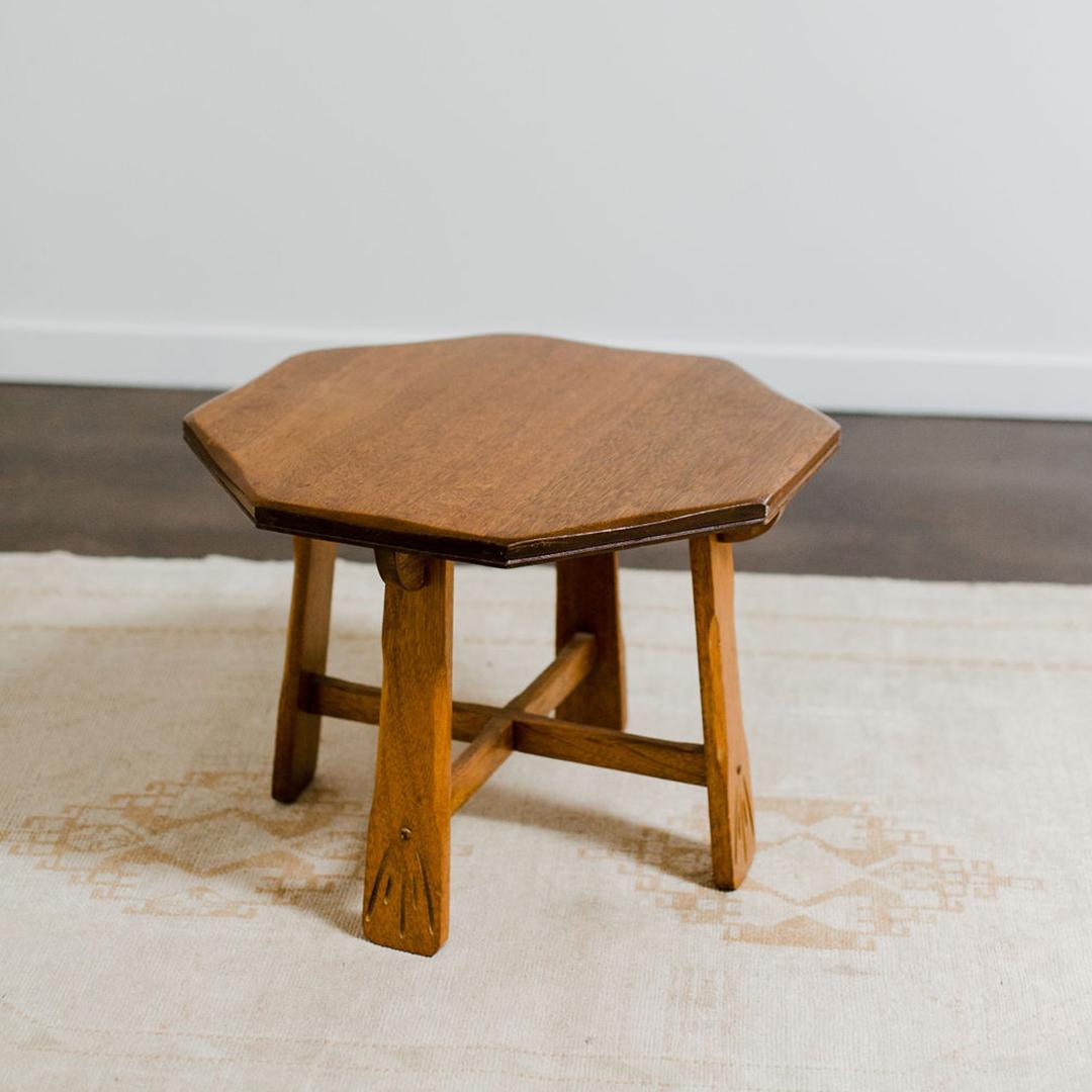 A meticulously crafted solid oak side table in the Arts and Craft style with splayed legs joined to curved cross-stretchers. Its sleek lines and distinctive octagonal shape exude sophistication while adding a touch of classic charm to any space.