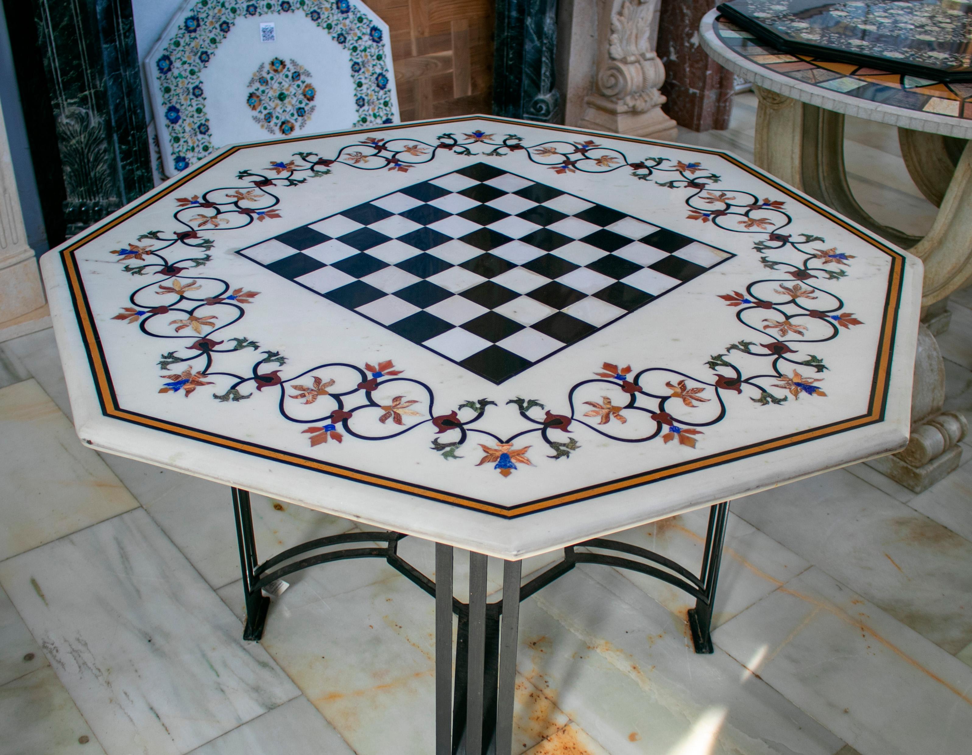 Plateau octogonal de table d'échecs en marbre blanc mosaïqué selon la technique italienne de la pierre dure, avec incrustations de lapis bleu, de jade vert, d'améthyste rose et d'autres pierres semi-précieuses.
 