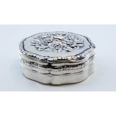Octagonal silver pill box with floral motifs on the hinged lid