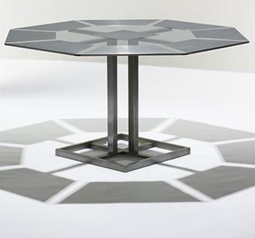 A very stylish geometric steel and glass octagonal dining table - Nadine Charteret has cleverly set the 8 trapezoidal metal 'place mats' around the perimeter of the glass table top, contrasting brushed steel and transparent glass - an excellent
