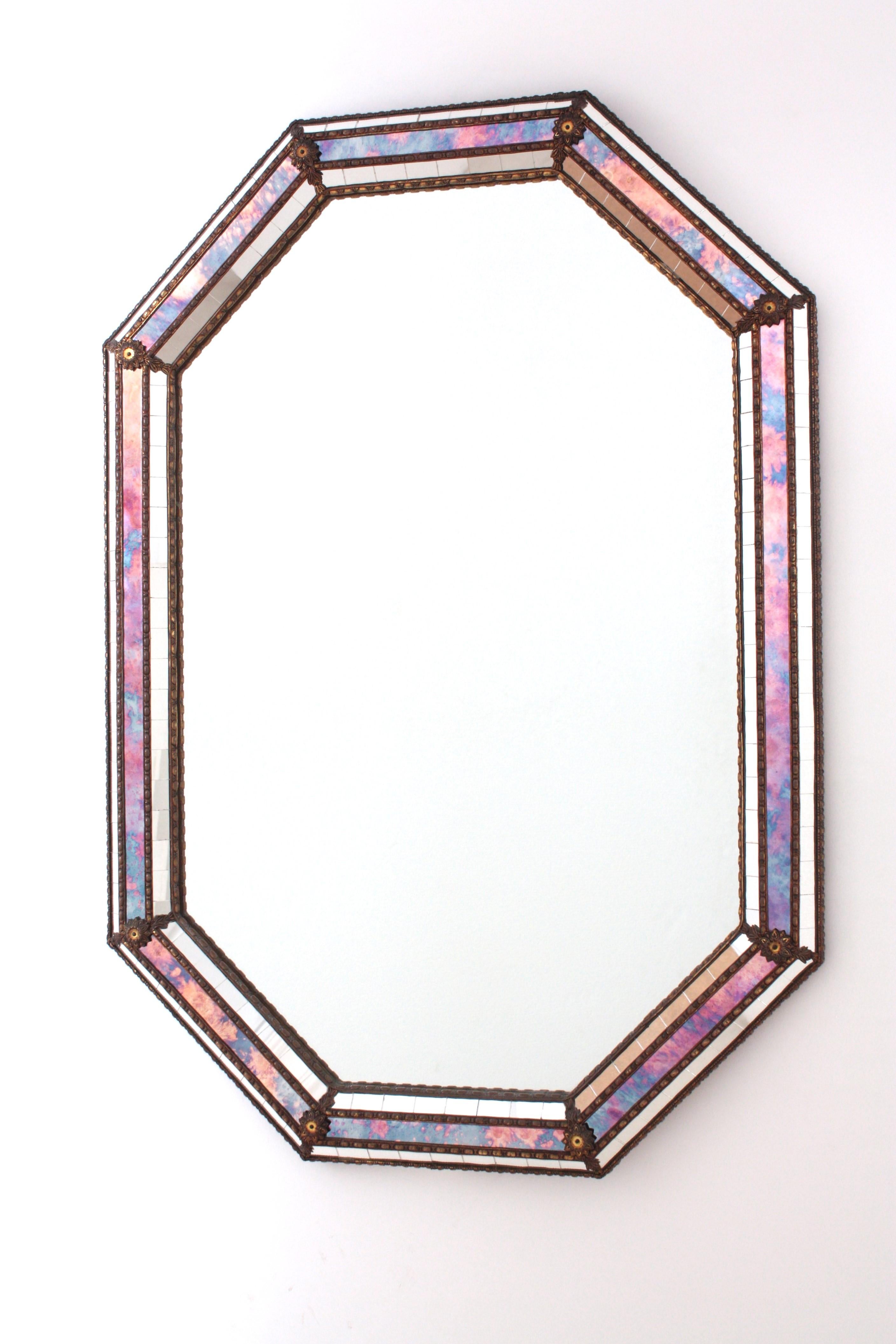 Miroir mural octogonal de style vénitien avec accents en métal doré, Espagne, années 1960
Ce miroir octogonal est doté d'un triple cadre. Deux couches de petits verres miroir en mosaïque et une couche centrale de verres miroir dans les tons rose,