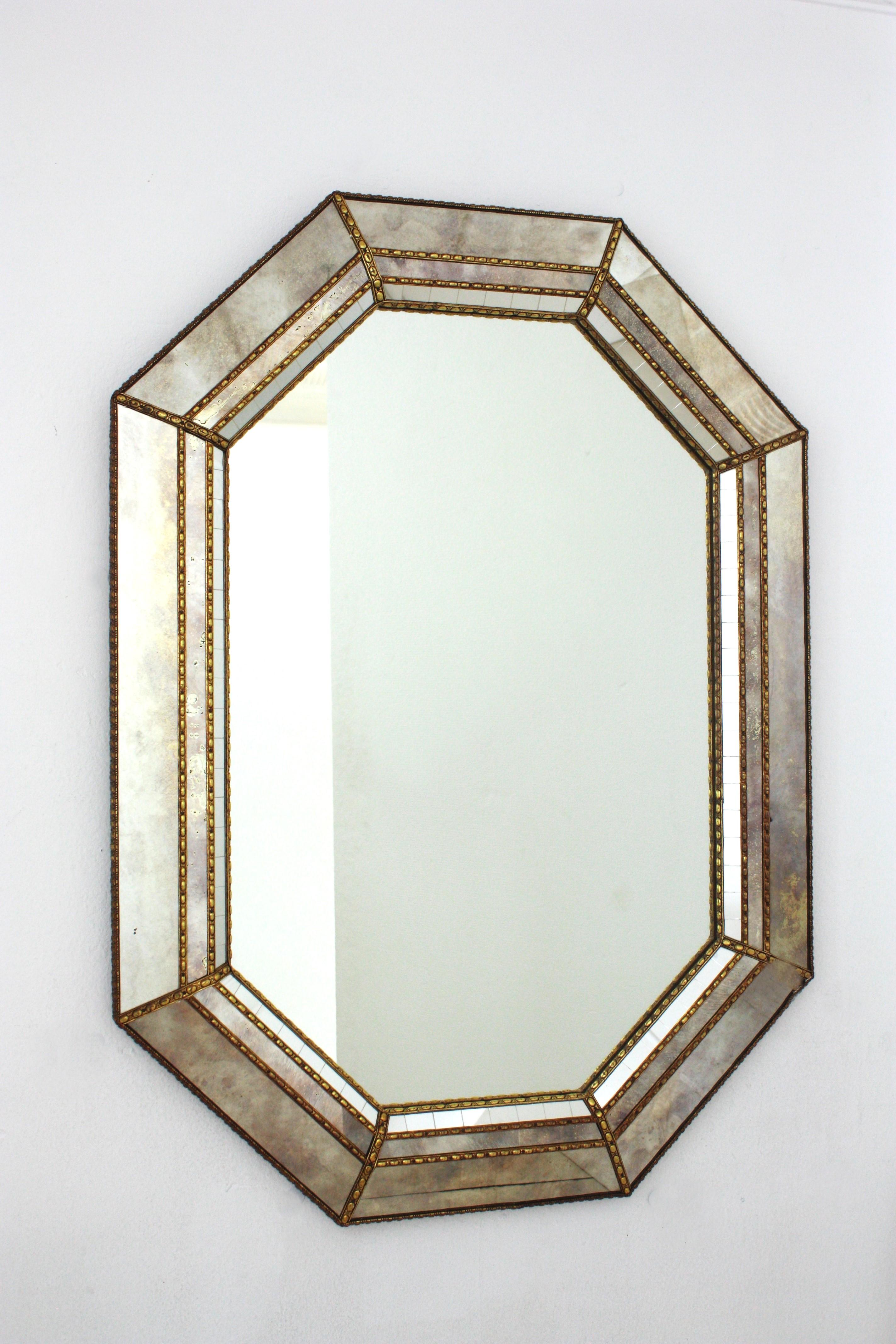 Elegant Venetian style Hollywood Regency octagonal mirror with iridiscent and mirror glass panels. Spain, 1960s
This glamorous mirror featuring a triple layered mirror frame made of brass. Octagon form with a frame that has three layers of