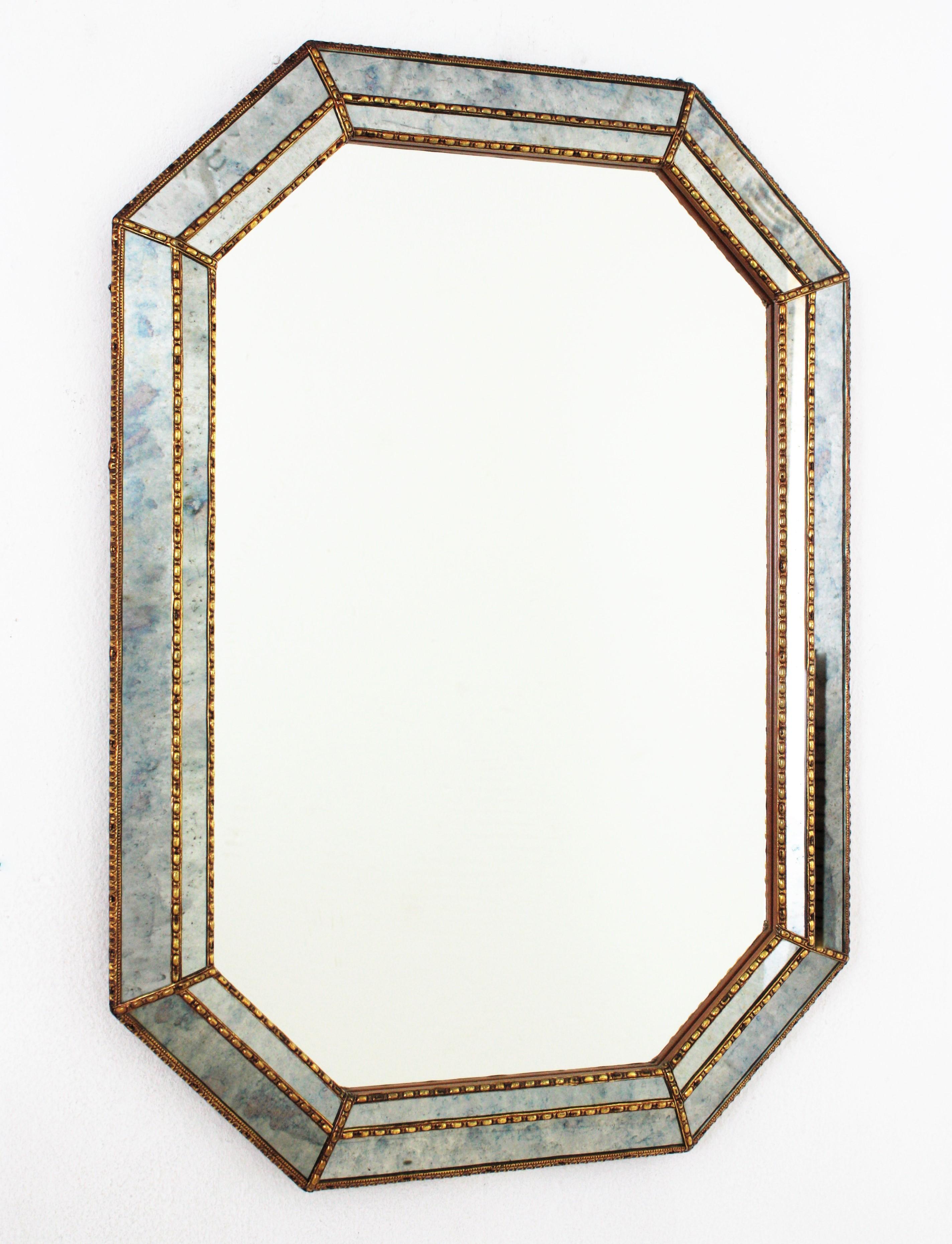 Cool Venetian Modern octagonal mirror with iridiscent mirror glass panels. Spain, 1960s
This glamorous mirror featuring a double layered mirror frame made of brass. Octagonal form with a frame that has two layers of decorative paneled mirrors. Both