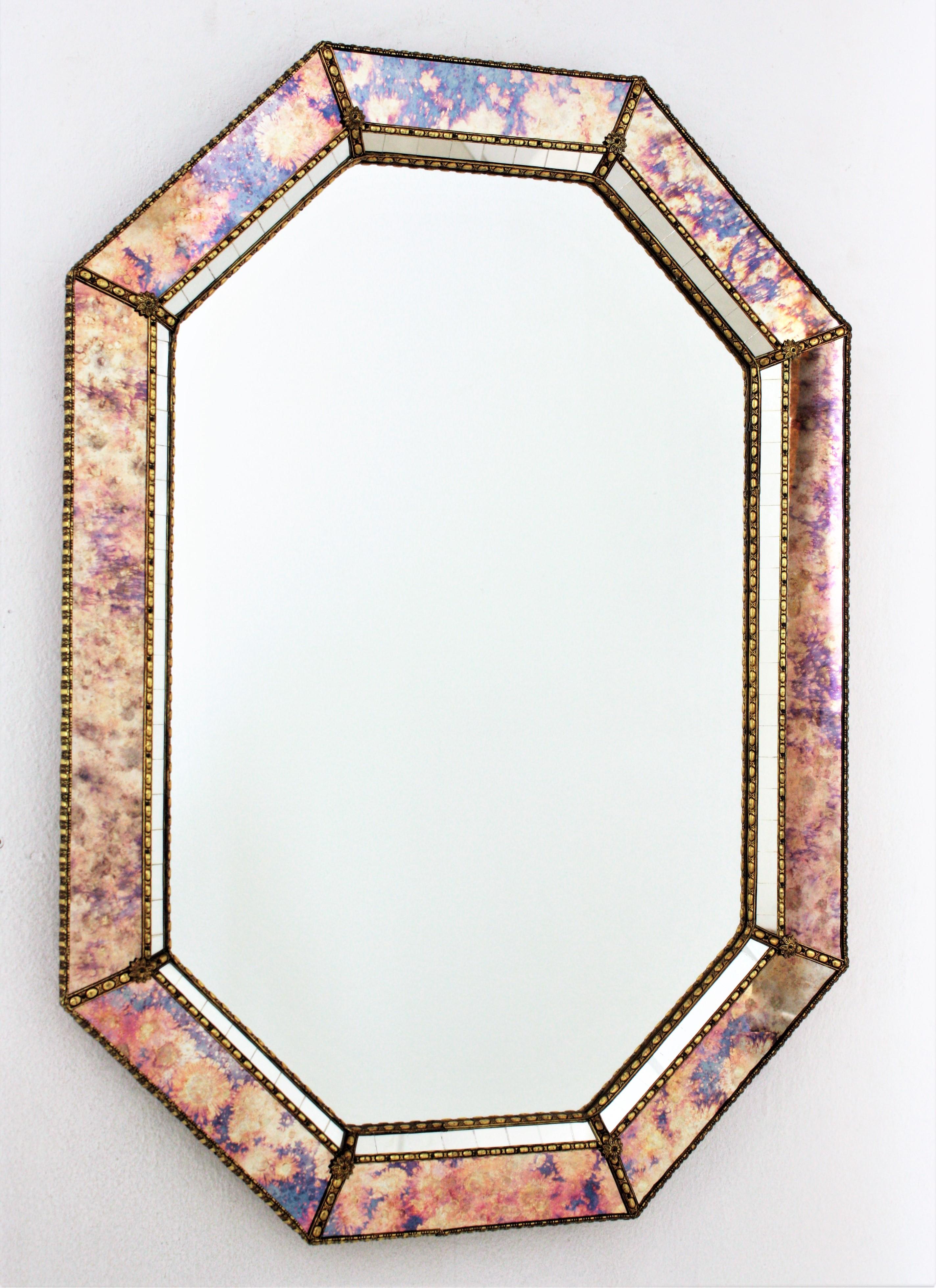Cool Venetian style Hollywood Regency octagonal mirror with iridiscent and mirror glass panels. Spain, 1960s
This glamorous mirror featuring a double layered mirror frame made of brass. Octagonal form with a frame that has two layers of decorative