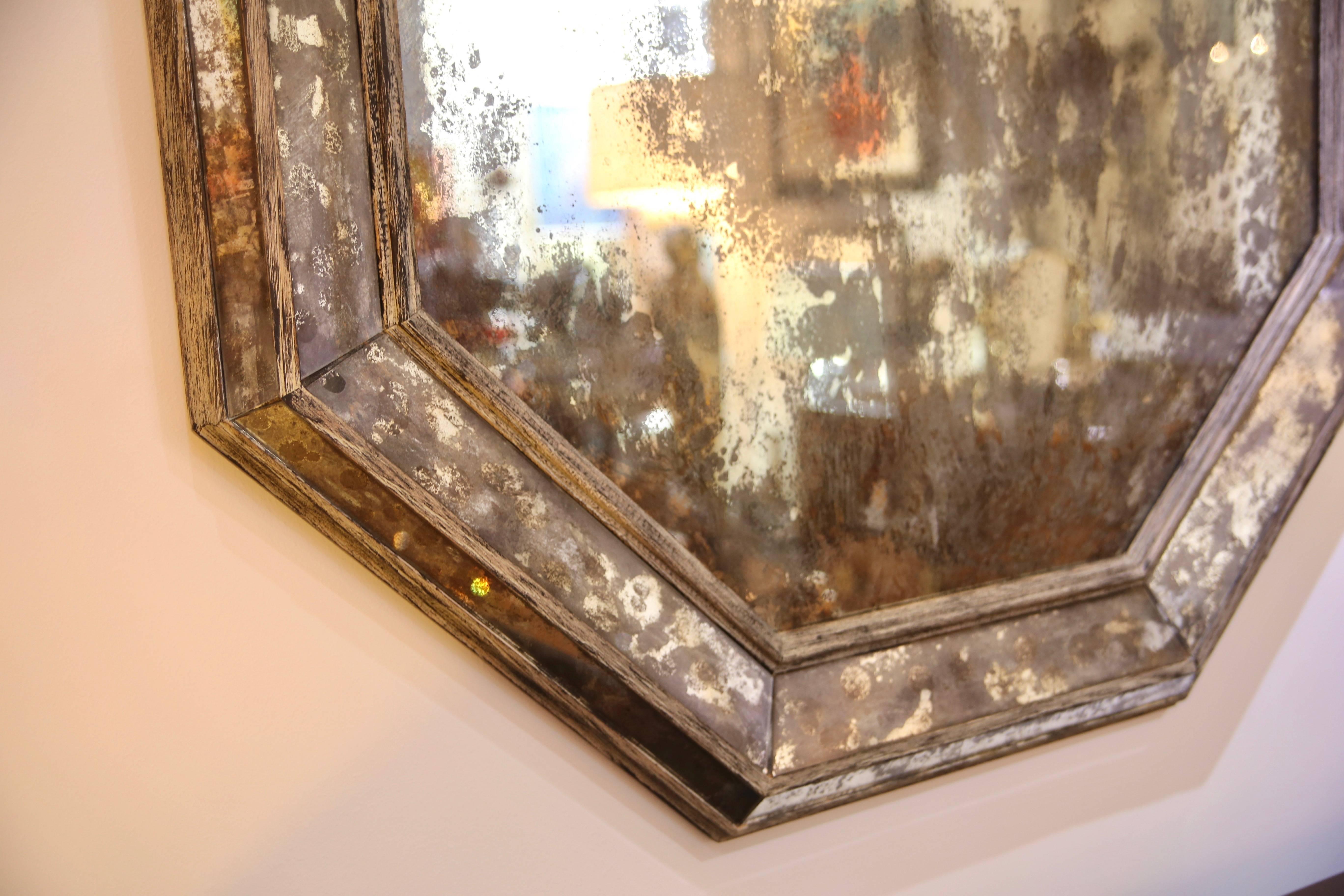 This large-scale octagonal wall mirror was created by Niermann Weeks and is finished with a distressed wood frame and antiqued mirror.
