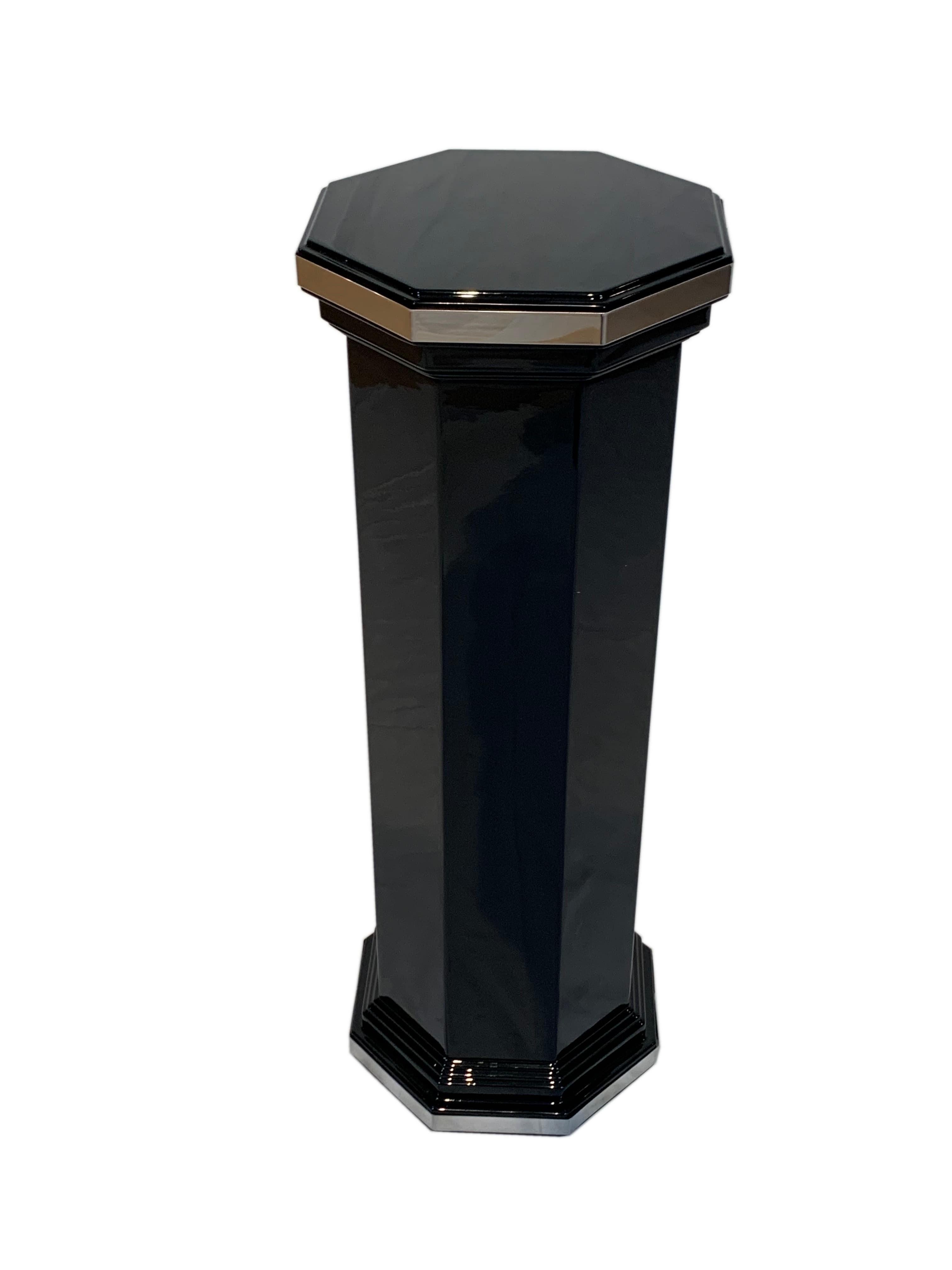 Elegant octagonal Art Deco column / pedestal from France, circa 1930

Black lacquered and high-gloss polished heavy hardwood. Finely stepped base and capital.
Around the top and bottom a polished chrome-colored stainless steel decorative