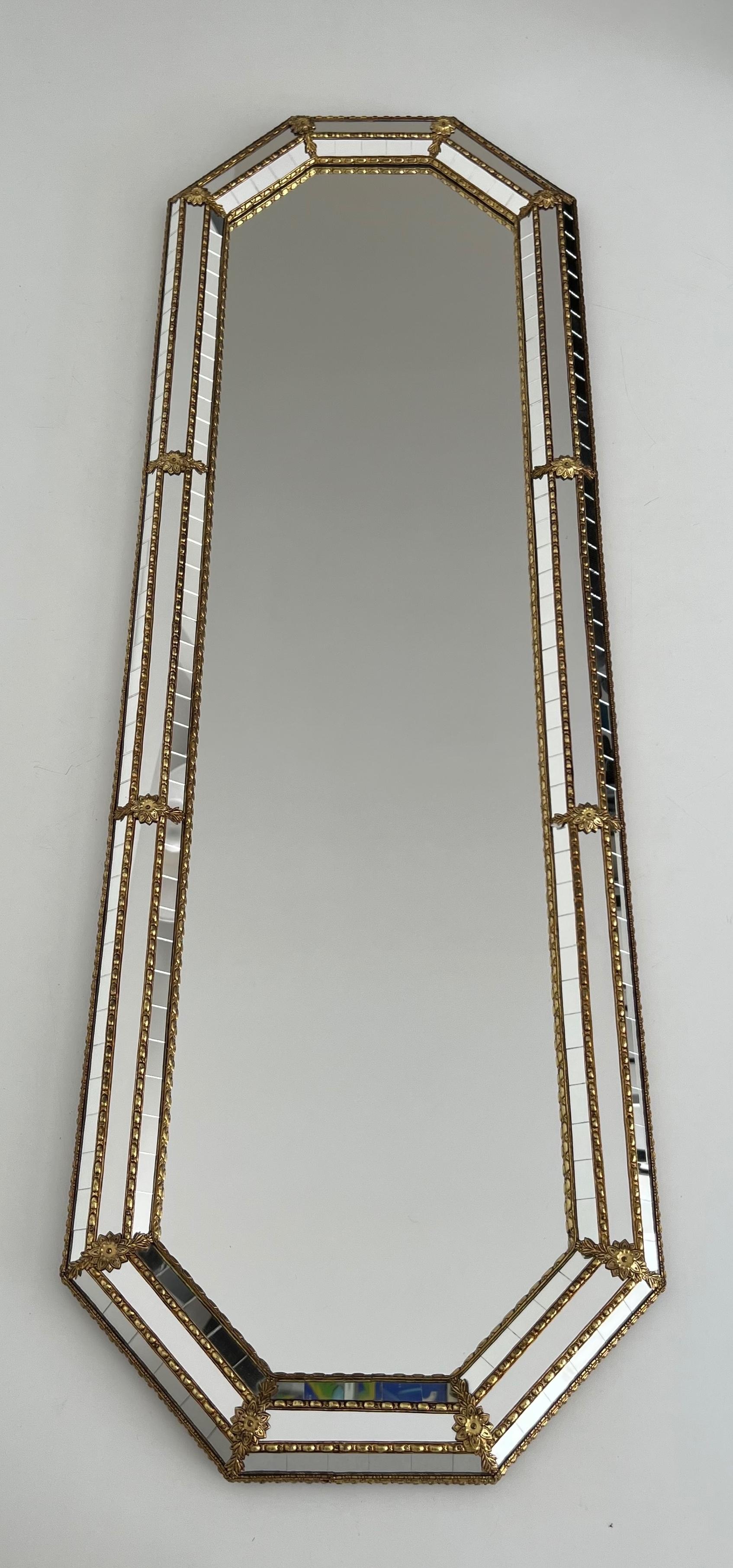 This very nice and elegant tall octogonal mirror is made of a central mirror surrounded by multi-facets mirrors with brass garlands. This is a French work. Circa 1970