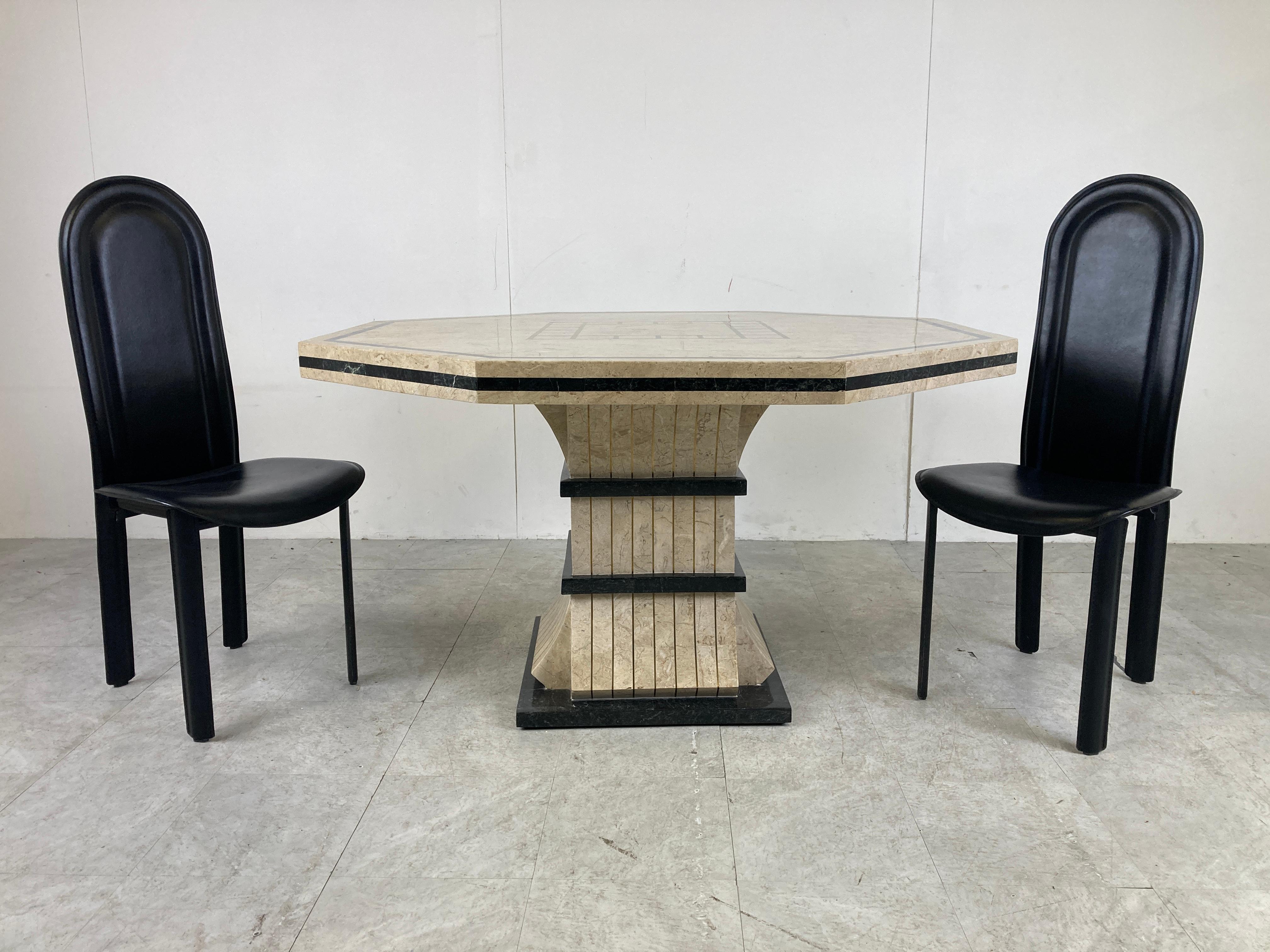 Beautiful dining table made from tesselated stone with an octogonal top and a nicely shaped base.

The use of black stone on both base and top create a nice contrast. The top also had inlaid brass, adding another nice touch. 

Can be combined