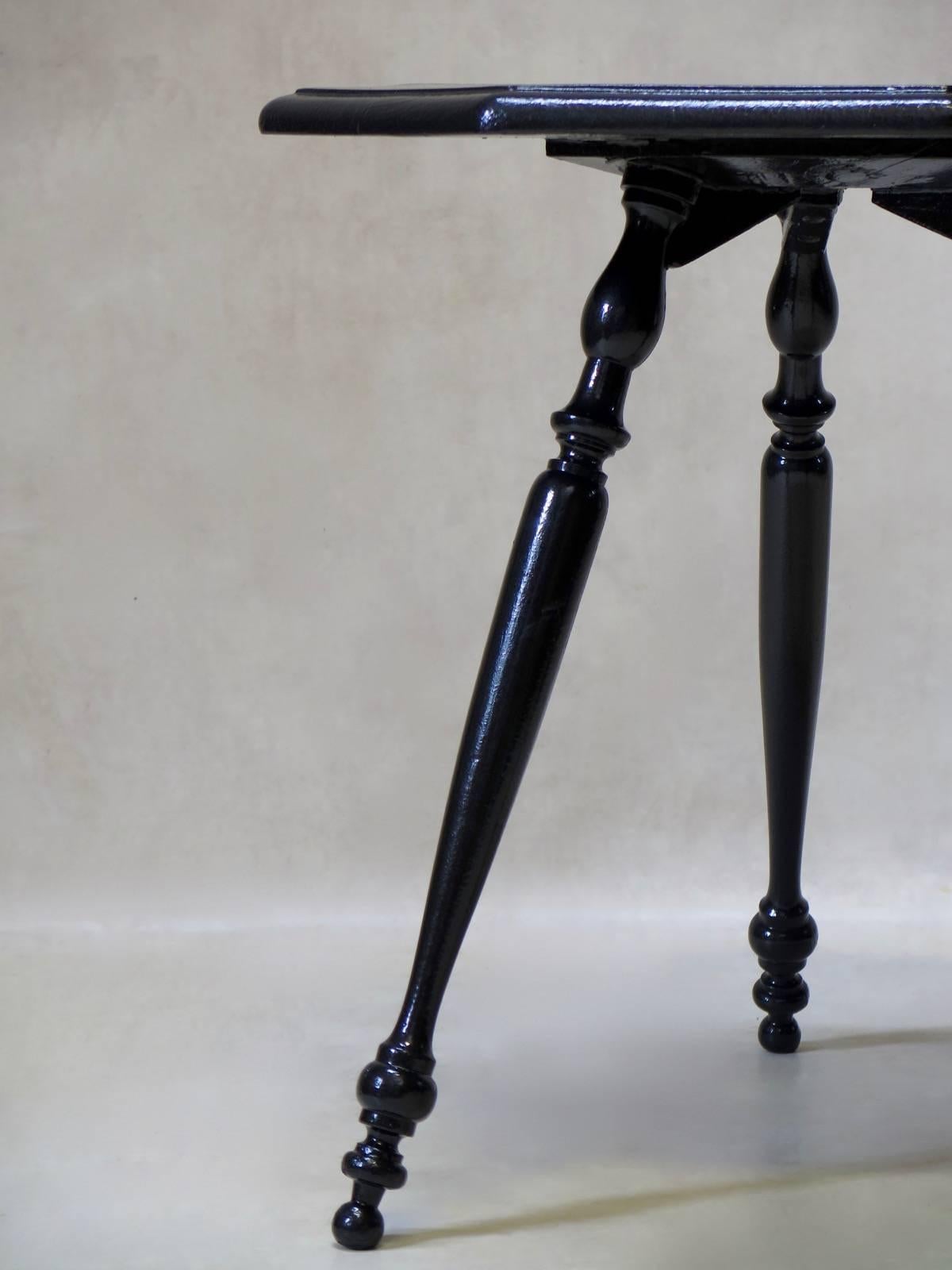 Unusual little side table with an octogonal top, raised on finely turned, splayed legs. Painted glossy black.