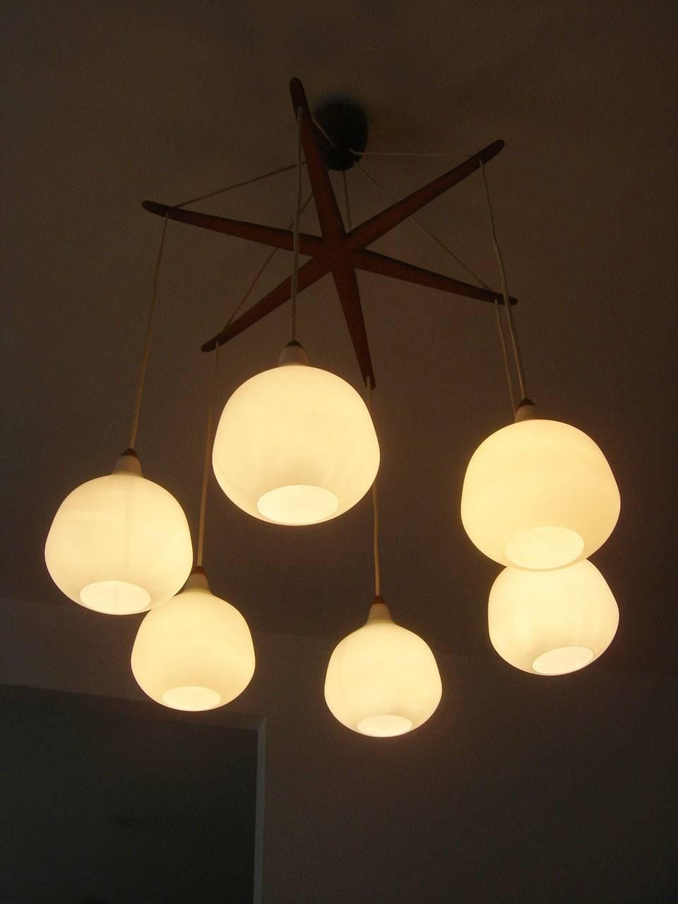 Exceptional Mid Century Modern chandelier or pendant lamp 'Octopus' with opaline shades and teak arms. Designed by Uno & Östen Kristiansson, 1957 for Luxus, Vittsjö, Sweden. 

Executed in opaline glass and teak wood, the lamp needs 6 x E27 / E26