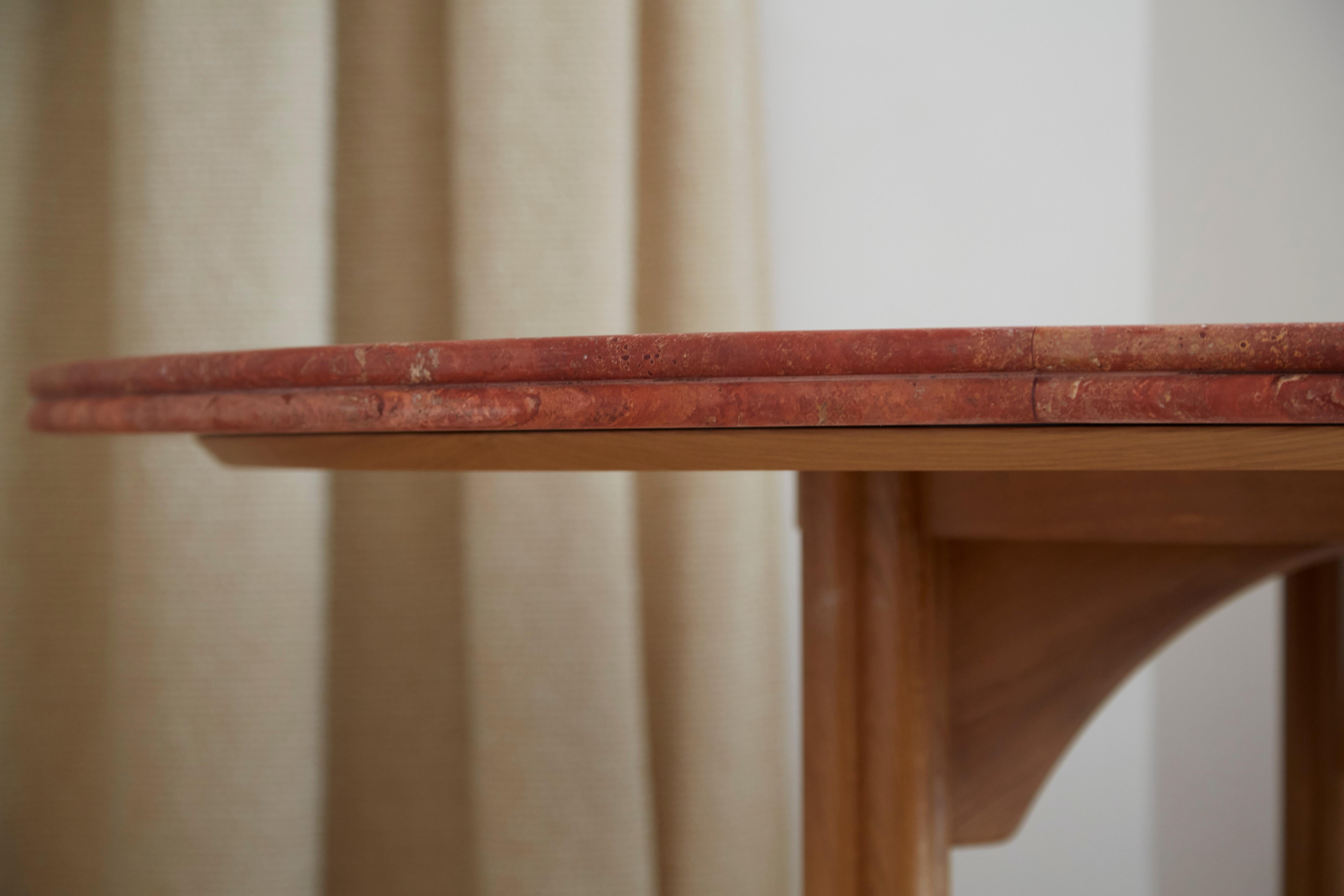 Table de salle à manger avec un double plateau rond, marqueterie de travertin rouge en forme de soleil, conçue par Laura Gonzalez. Pieds en chêne clair avec détails ronds et courbes. Tout est fabriqué en France.