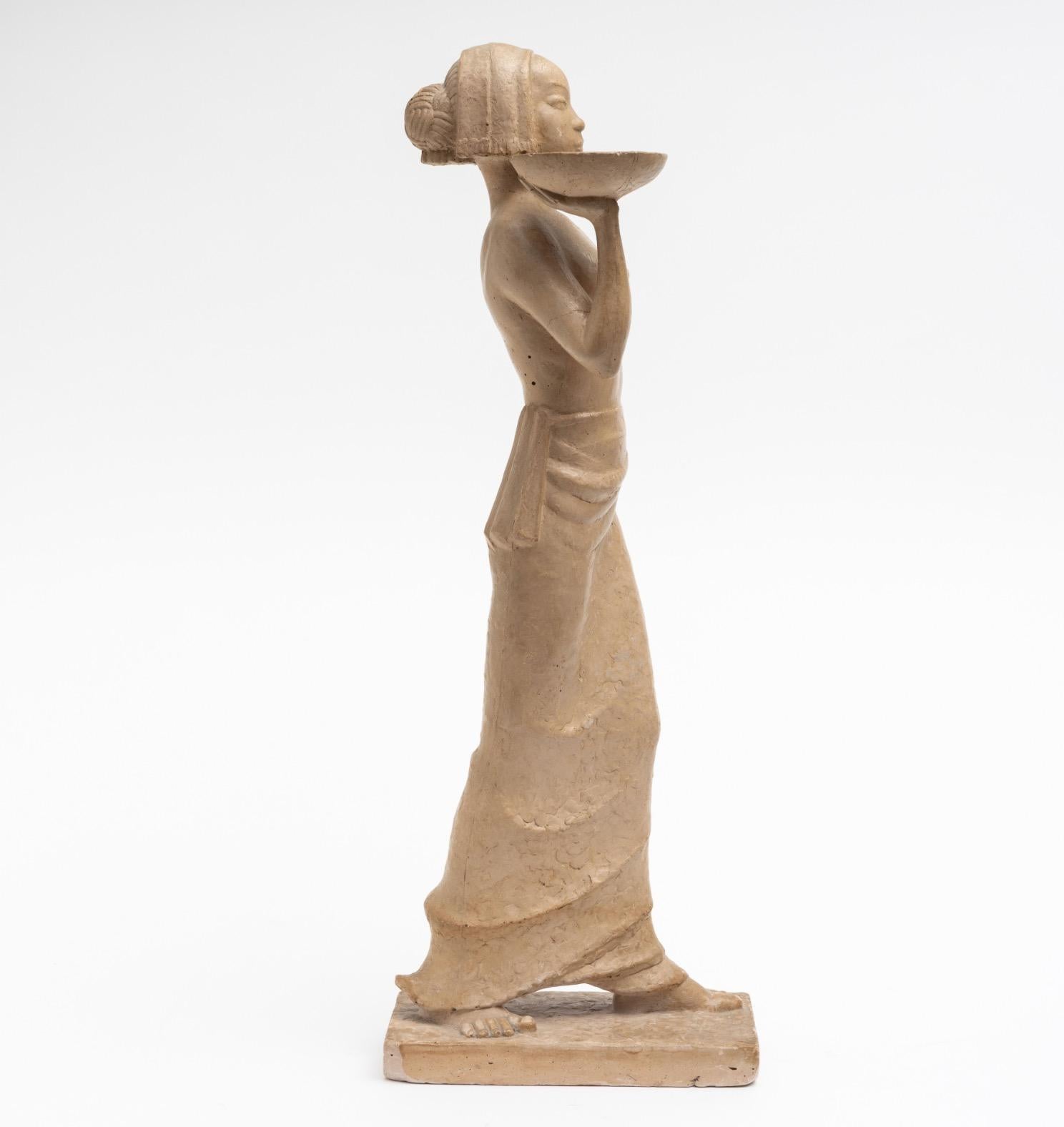 Scultura in gesso dipinta in terracotta art déco di un'odalisca parzialmente nuda che cammina tenendo un vassoio, firmata e datata 