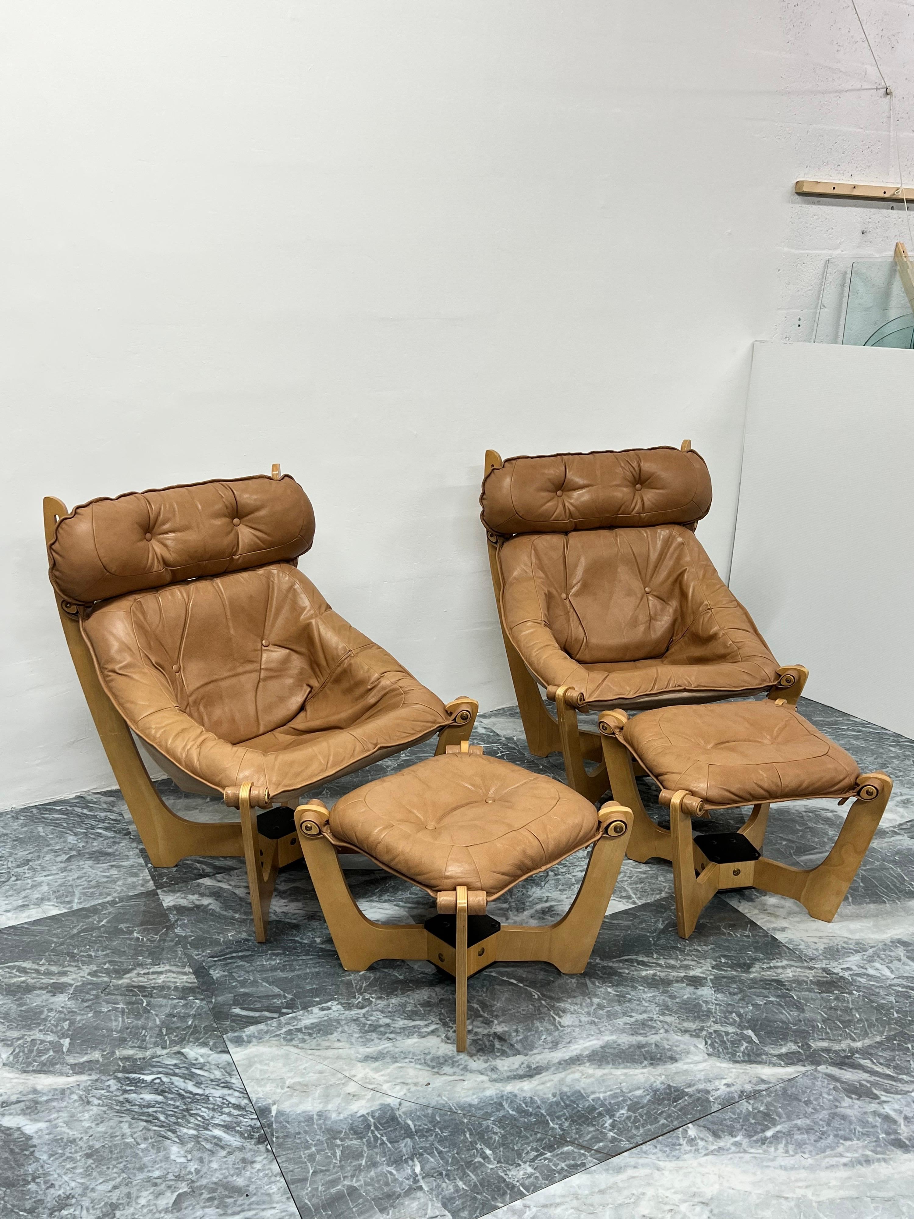 Pair of lounge chairs with tan leather sling seats suspended from light blonde stained wood frame with footrest by Odd Knutsen for IMG Norway.

Dimensions:
Chair - W 30