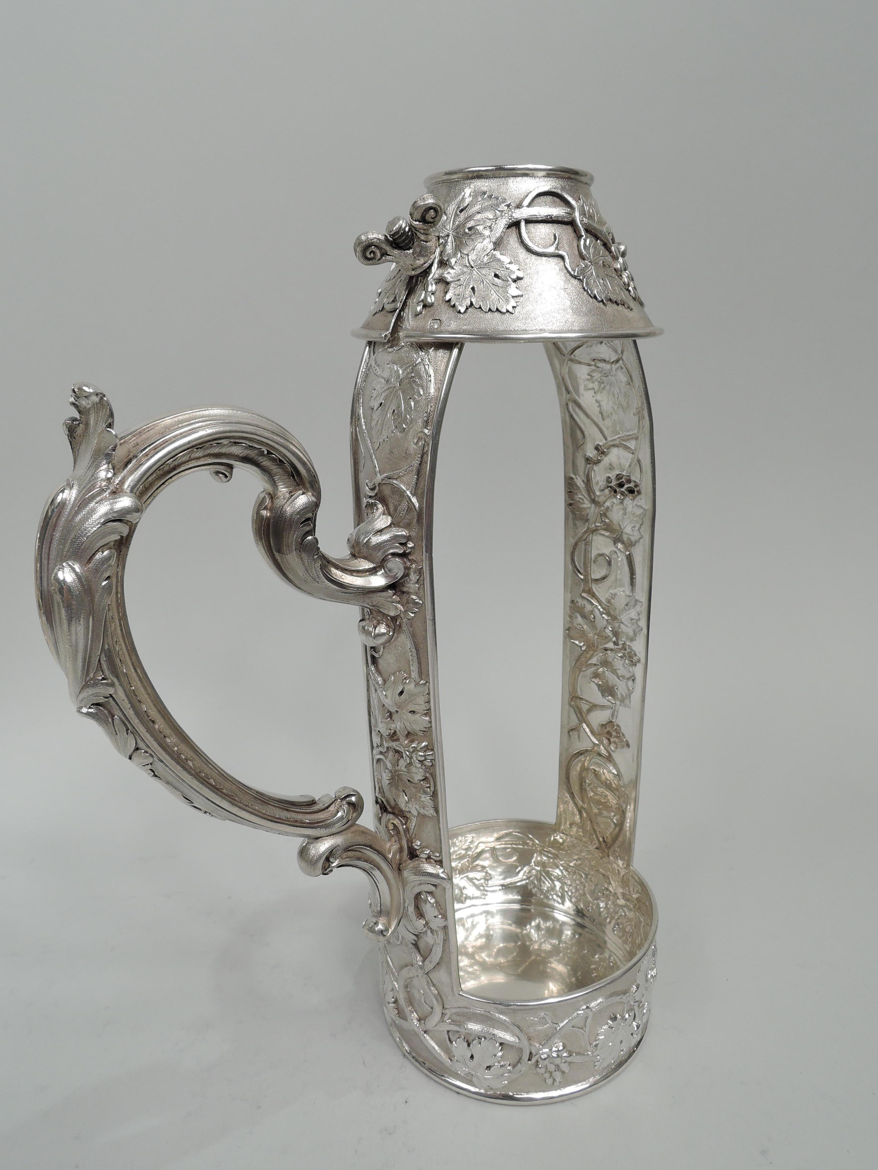 Belle Epoque Classical 950 silver wine bottle holder. Made by Odiot in France, ca 1890. Open body comprising two rectilinear supports mounted to round bowl with straight sides. Conical neck with adjustable screws. Leaf-capped double-scroll handle.