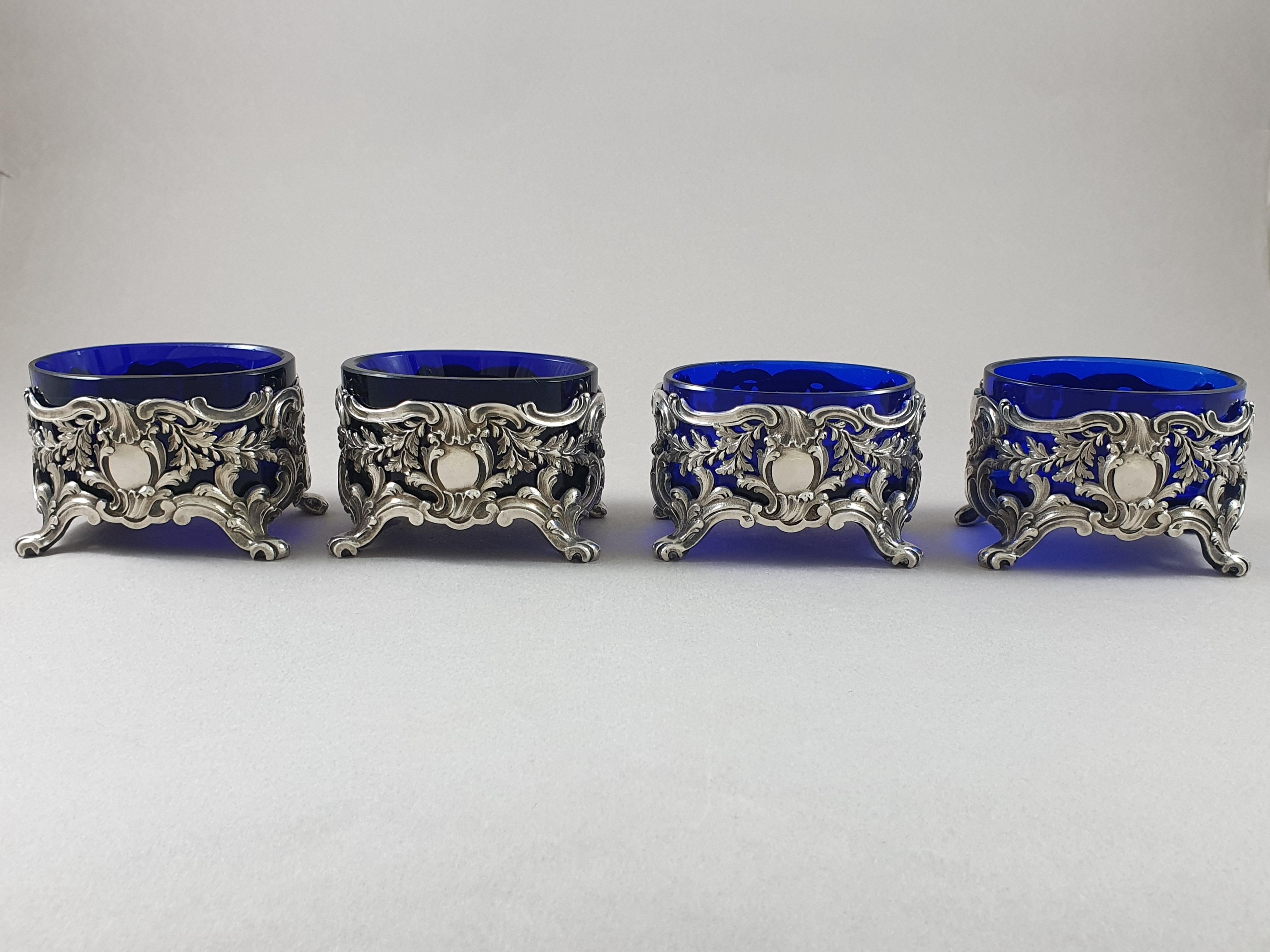 Beautiful set of 4 salt cellars in sterling silver from the 19th century, the interior in blue crystal.

They rest on feet ending in foliage, decoration of foliage, leaves and medallions.

Hallmarked Minerva 1st title for 950/1000 purity silver.