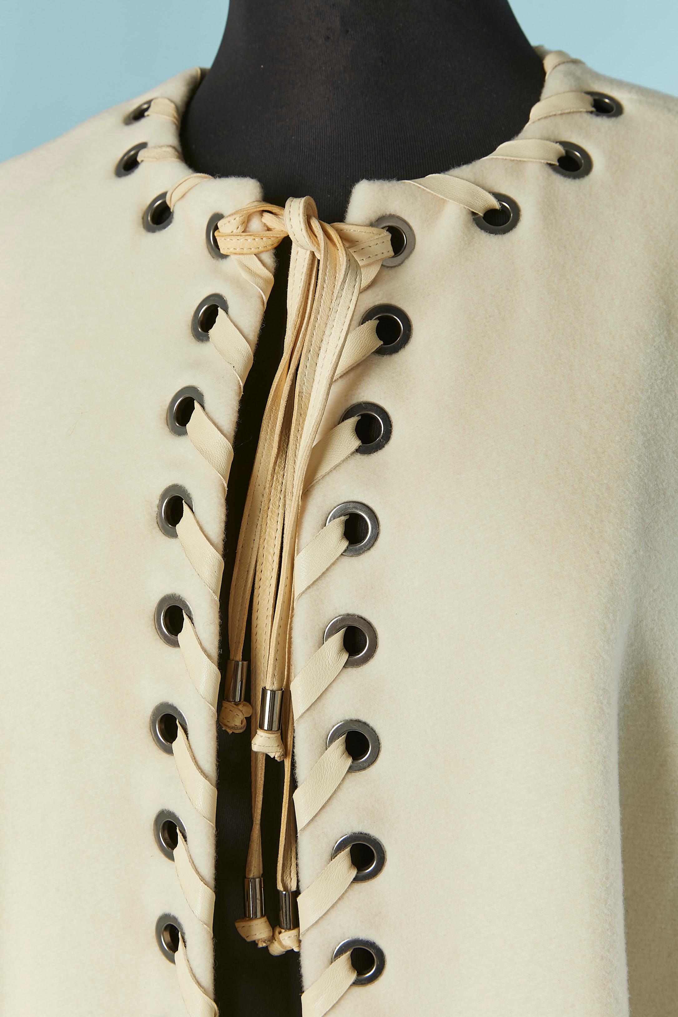 Cappotto della linea A di colore bianco sporco con lacci in pelle. Composizione del tessuto principale: 70% lana, 20% nylon, 10% cashmere. Fodera in cotone e modal. 
Tasca su entrambi i lati. 
TAGLIA 38 (Fr) M 