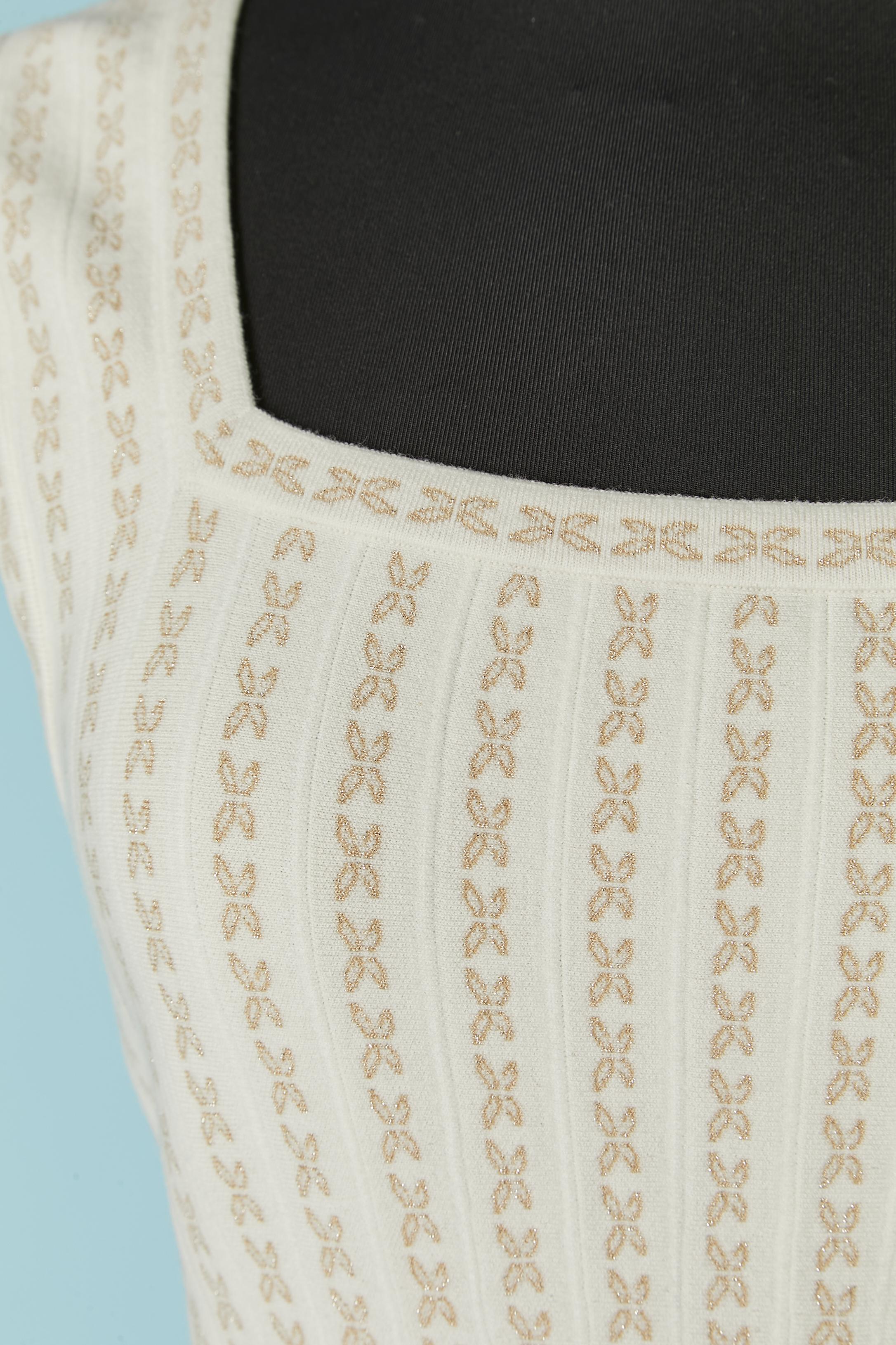 Abito senza maniche in jacquard plissettato in lurex bianco sporco e oro. Composizione del tessuto: 56% lana, 15% nylon, 12% poliestere, 12% rayon, 3% metallo, 2% elastan. 
Chiusura con zip invisibile sul lato sinistro.
TAGLIA 38 (Fr) M 