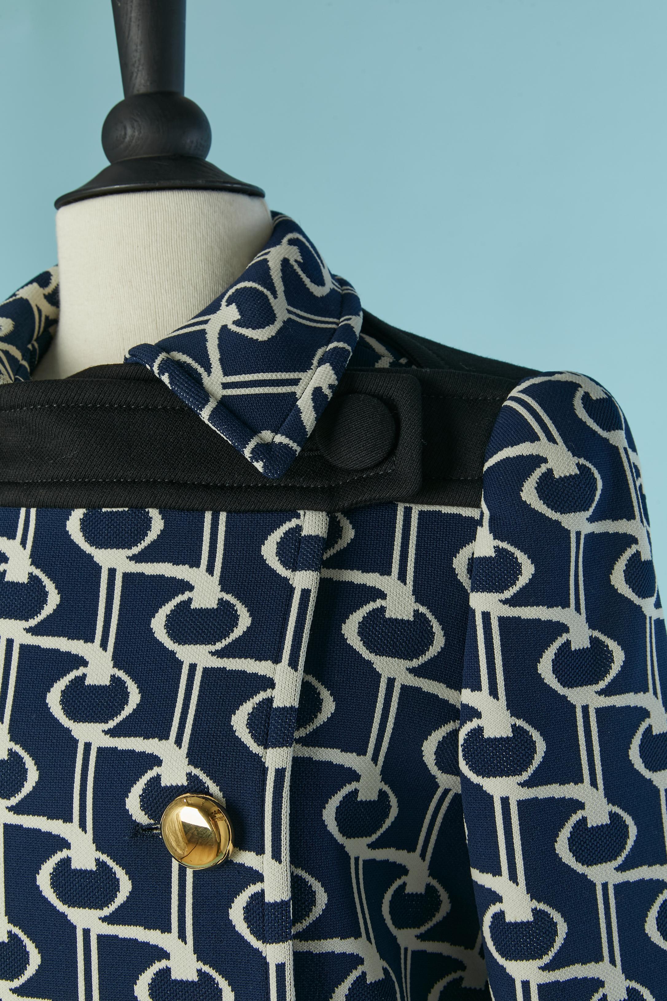 Cappotto doppiopetto in jersey jacquard bianco sporco e navy. Tessuto del guscio: 100% poliestere. Fodera: 100% rayon. Bottone in plastica dorata e chiusura ad asola sul davanti + uno  pulsante Fabrice in alto a sinistra. Spacco sul lato destro sul