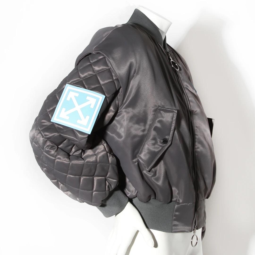 Off-White by Virgil Abloh Bomber Jacket 
Made in Italy 
Grey Nylon 
Ribbed knit baseball collar 
Ribbed knit hem and cuffs
Quilted balloon sleeves 
Angled flap pockets on each side of the jacket 
Pockets have gunmetal snap closures 
Gunmetal tone O