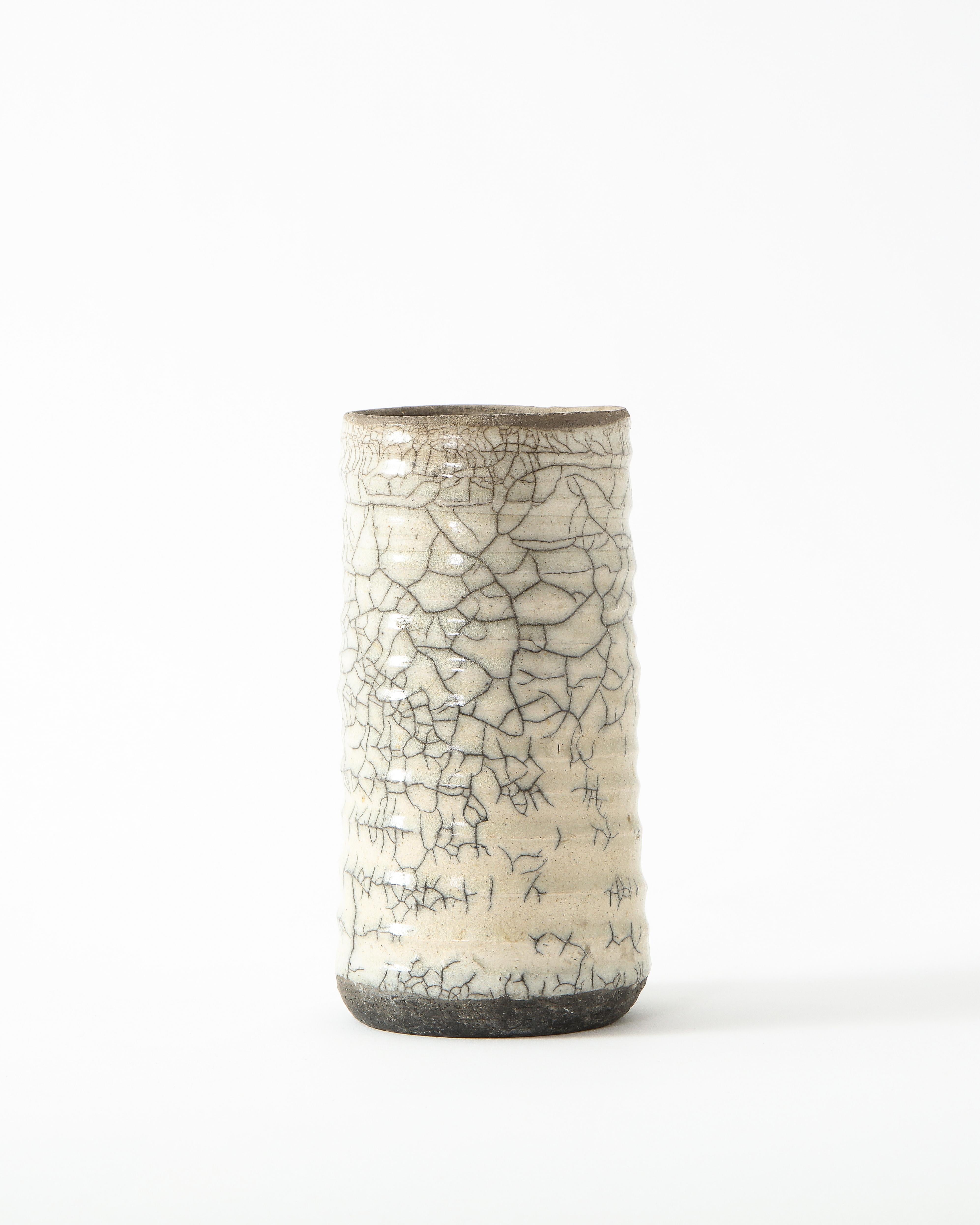 Small and narrow off-white ceramic vase with intricate crackling. Simple and poetic.