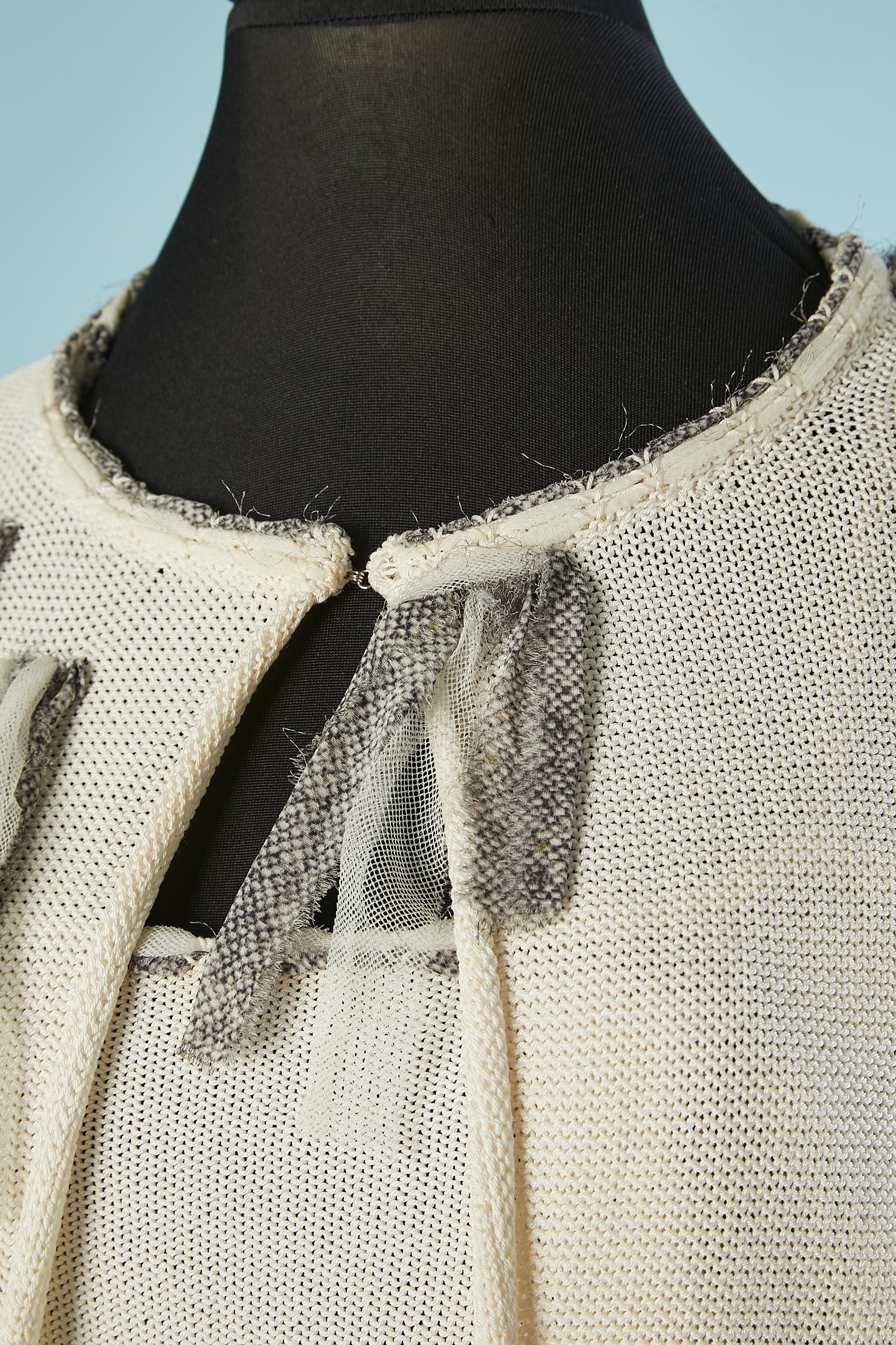 Off-white knit cardigan and bustier ensemble . Fabric composition: 54% rayon, 41% cotton, 2,5% silk, 2,5% nylon. Fringes of printed chiffon and tulle embellishement. 
One hook&eye in the middle top of the cardigan. Braid made of chiffon and tulle on