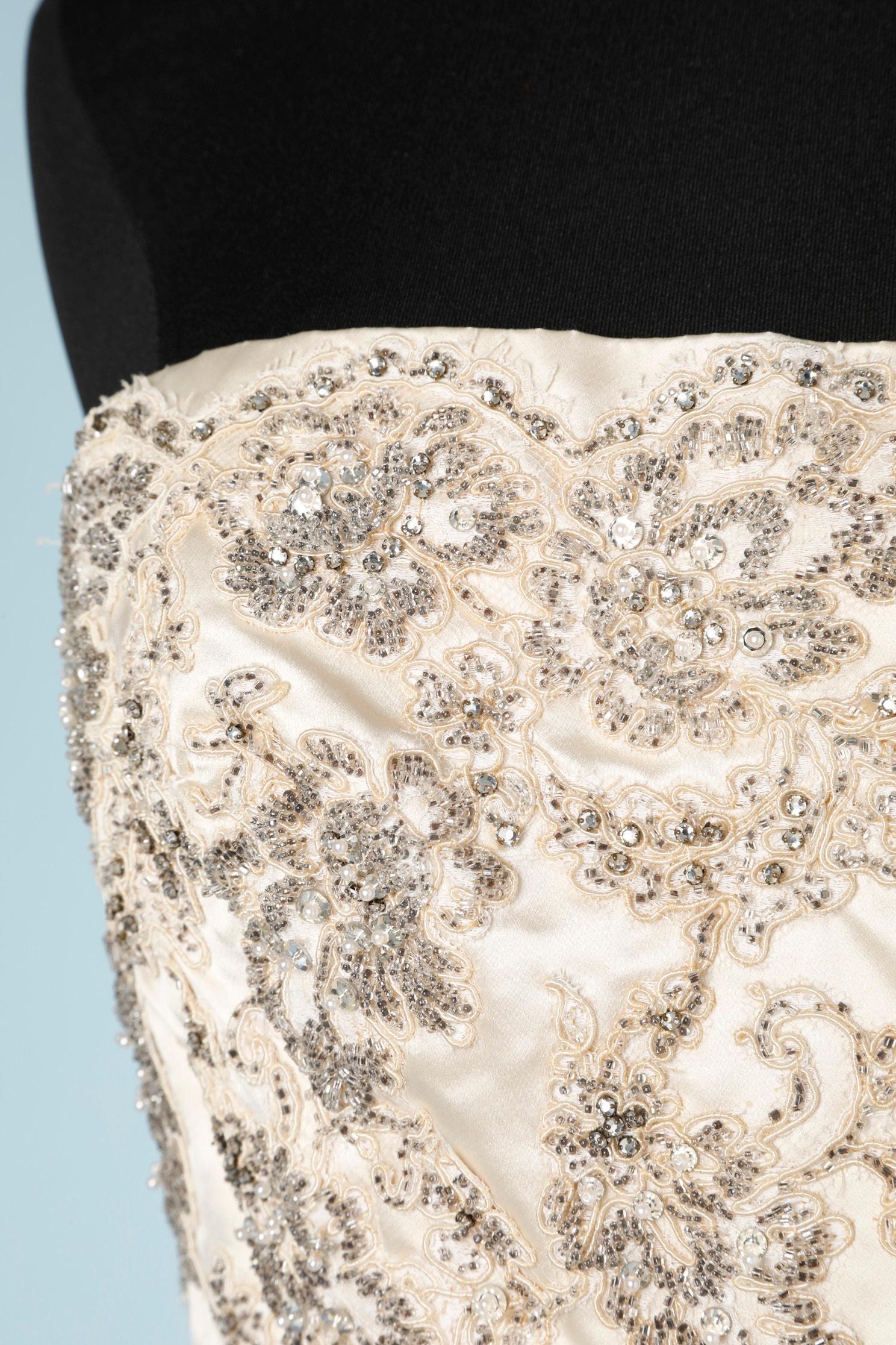 Abito da sera in raso bianco sporco con perline. Sottoveste in tulle e acetato. Bustier disossato. Chiusura con zip e gancio sulla parte centrale della schiena.
taglia 38 (FR) M 