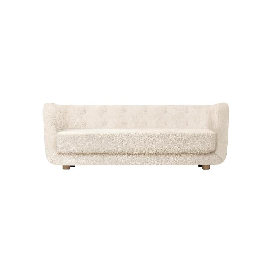Off white sheepskin and smoked oak Vilhelm sofa by Lassen
Dimensions: W 217 x D 88 x H 80 cm 
Materials: sheepskin, oak.

Vilhelm is a beautiful padded three-seater sofa designed by Flemming Lassen in 1935. A sofa must be able to function in