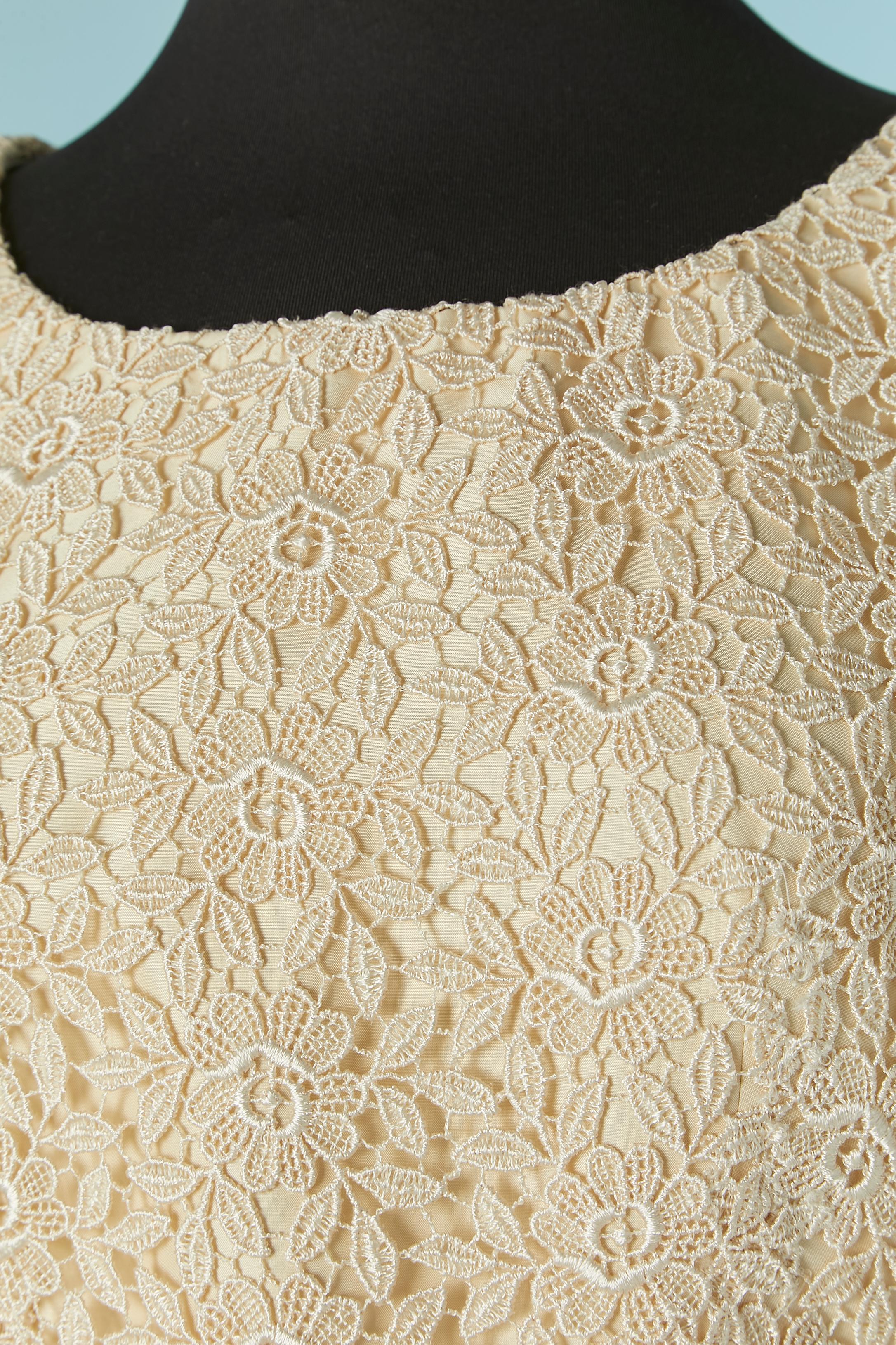 Robe de mariée en soie blanc cassé et dentelle guipure. Pad d'épaule. Noeud sur le devant au niveau de la taille. Fermeture à glissière au milieu du dos + fermeture auto-agrippante à la ceinture. 
Traînée courte. 
Longueur totale devant =