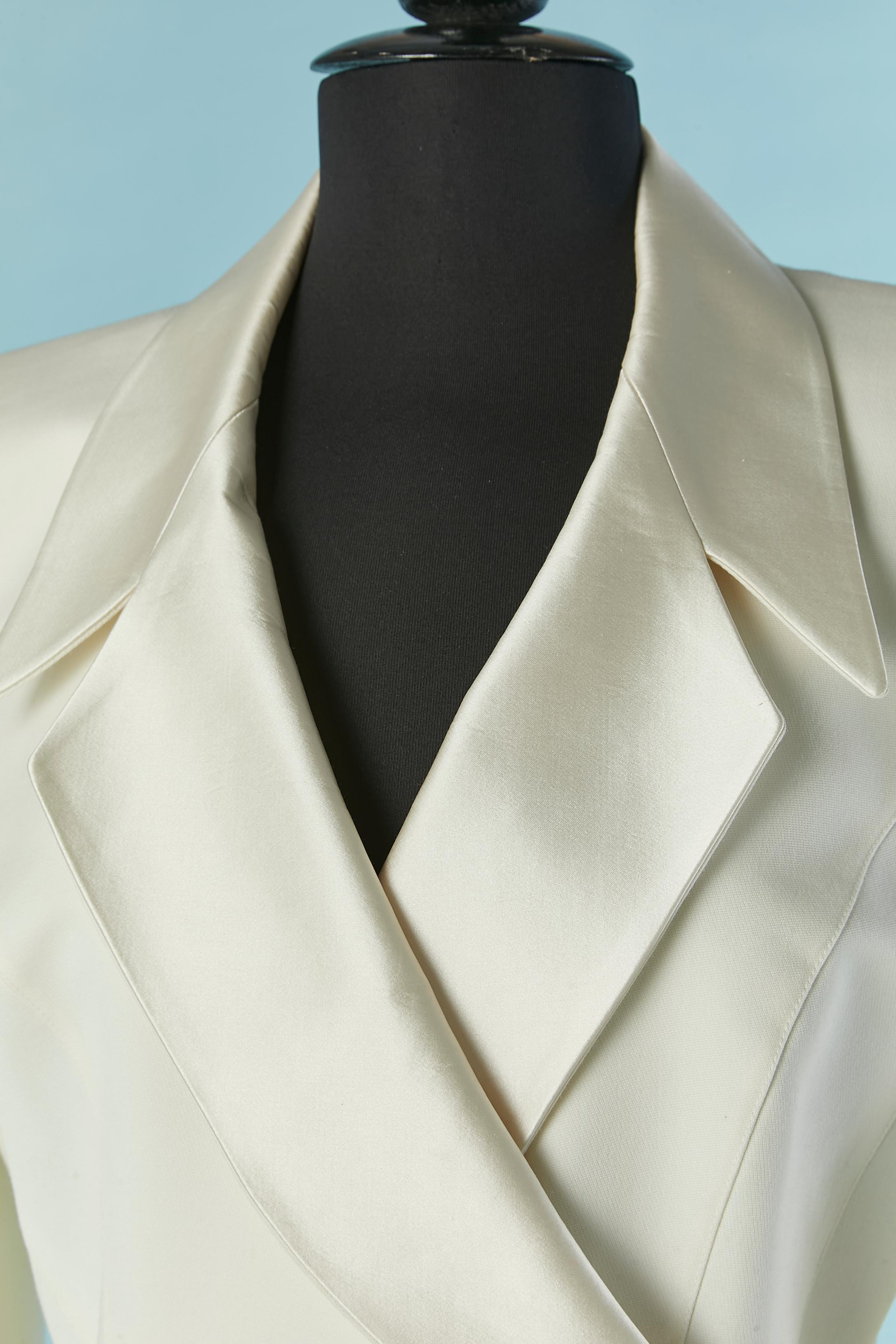 Jupe écrue - tailleur Tuxedo avec veste à double boutonnage et broche en strass. Composition du tissu principal : 100 laine. Composition du col : 60% coton, 40% soie. Doublure : 100% acétate. 
Pad d'épaule. Découpage. Fermeture par