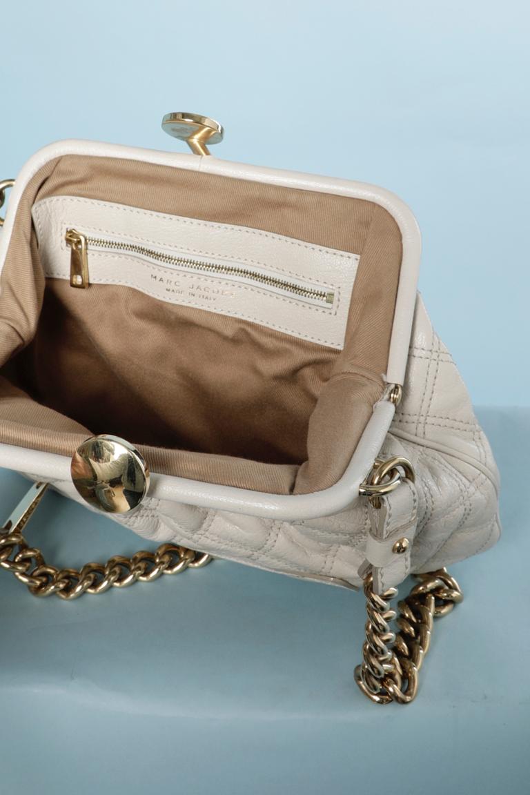 Off-white Ledertasche mit Steppnähten und goldener Metallkette. Braunes Baumwollfutter. Eine Tasche mit Reißverschluss innen und eine mit Reißverschluss außen. 
Größe 20cm X 32 cm X 8 cm
