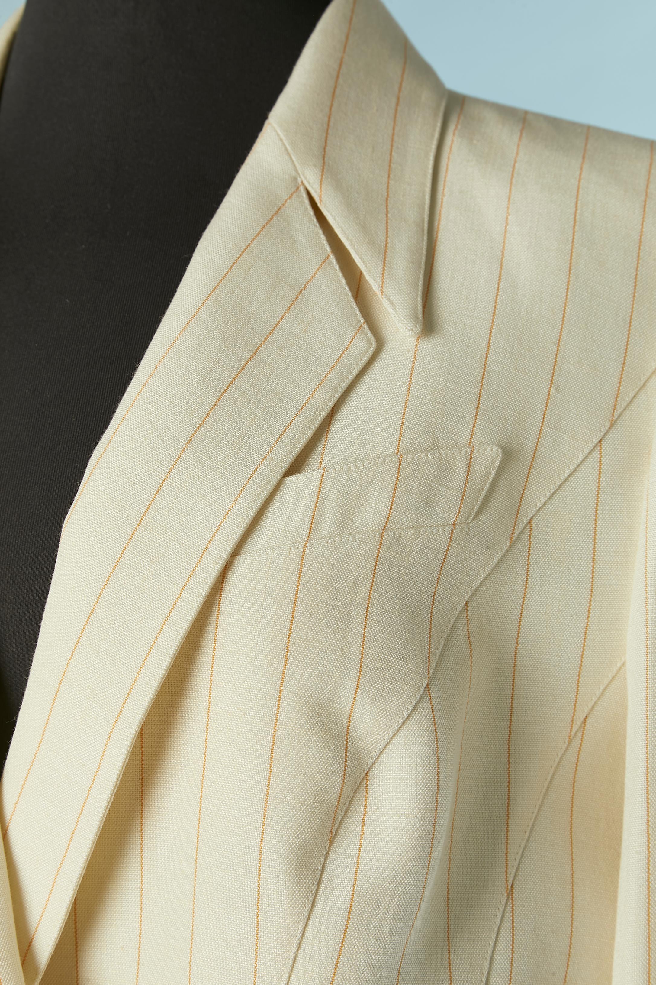Off-white trouser-suit with orange pin striped.
Main fabric composition: 69% rayon, 30% linen, 1% polyester. Acetate lining. 
Thin shoulder pad. Snap cover with fabric closure on the top front and on the cuffs. Split on the back side of the