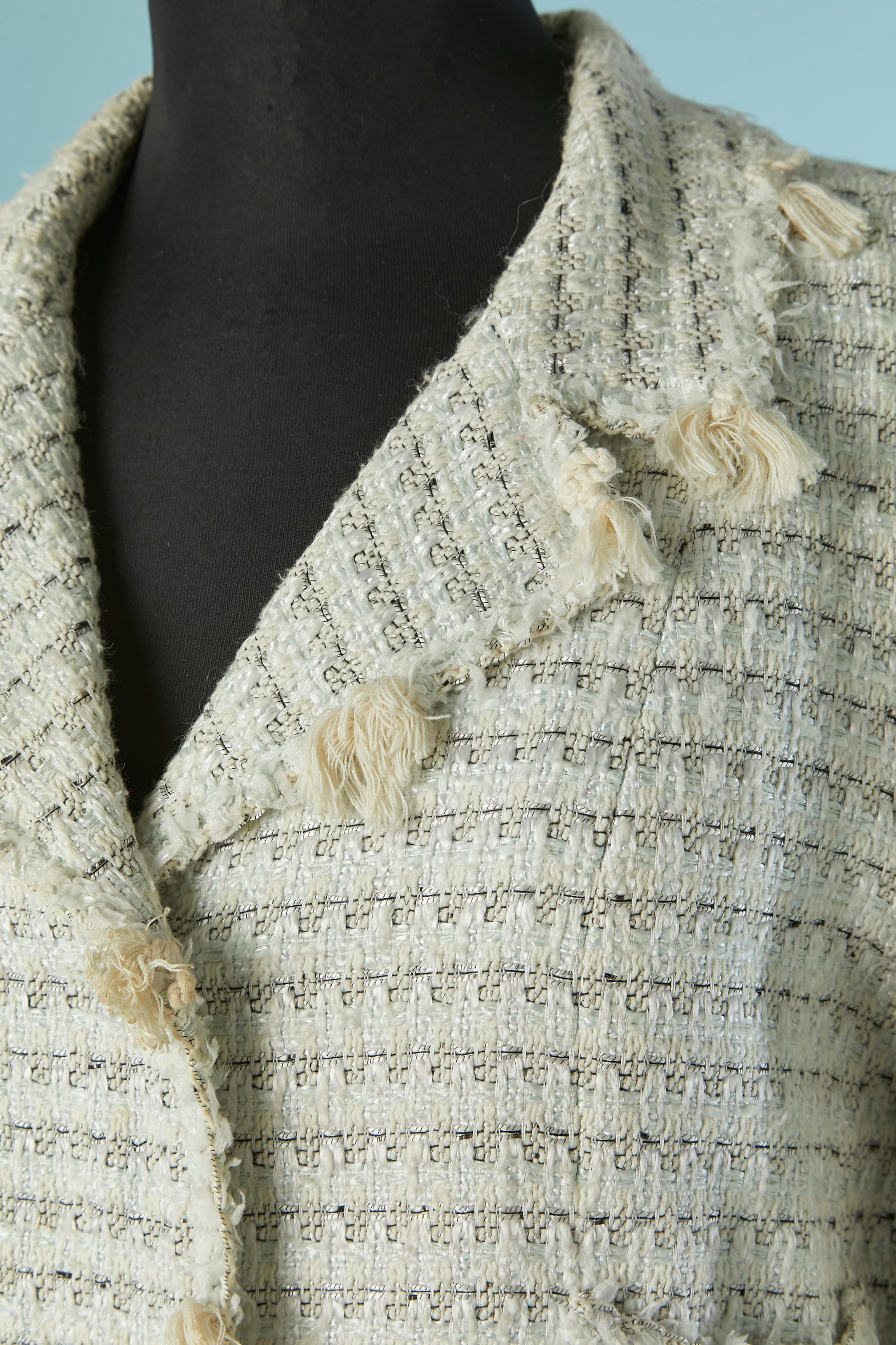 Giacca monopetto in tweed bianco sporco con abbellimento in nappe di cotone. 
Composizione del tweed: 52% cotone, 32% rayon, 14% lino, 2% poliestere. Fodera con marchio: 96% seta, 4% elastan. 
Bottone e asola con marchio sul centro davanti e sui