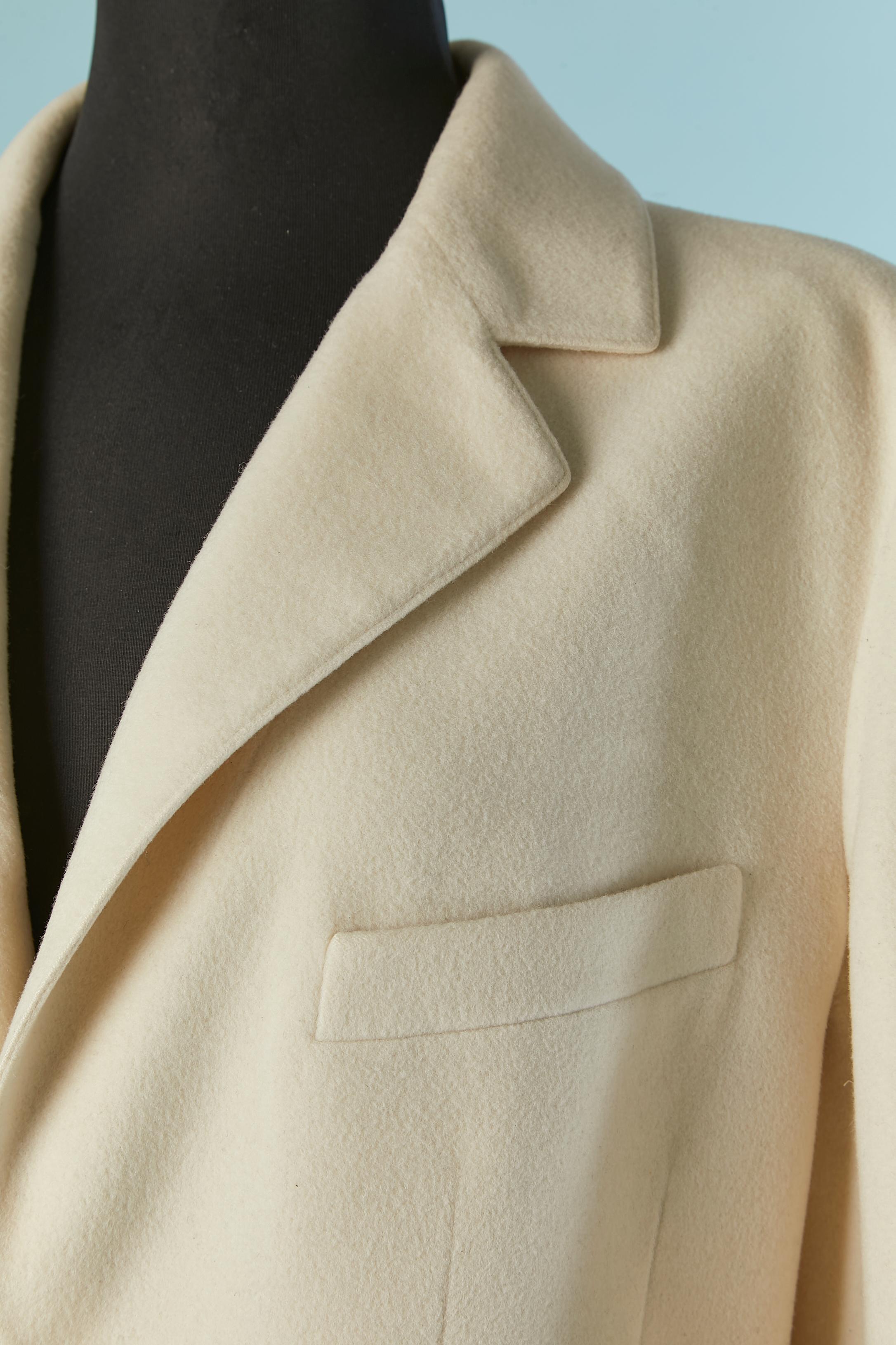Veste croisée en laine blanc cassé. Doublure en soie de marque. Pad d'épaule. Bouton et boutonnière marqués sur le milieu du devant et sur le poignet. Chaîne à l'intérieur sur le bord inférieur. 
TAILLE 42 (Fr) M/L 