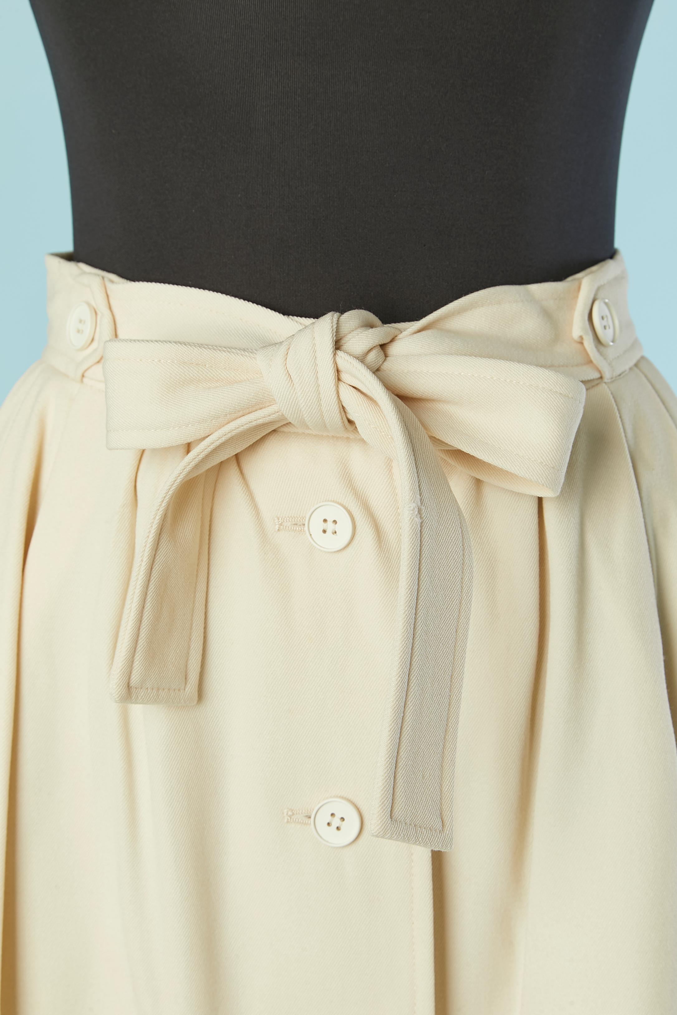 Gonna in lana bianco sporco con chiusura a bottoni sul centro davanti.  Fodera in acetato o rayon. 
Mezza cintura nella stessa stoffa. 
Tasca su entrambi i lati.
TAGLIA 34 (Fr) XS 
