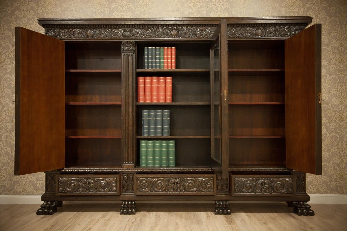 We present you this piece of furniture of a grand size, circa 1930, manufactured in Germany. It is made of oakwood and walnut burl. It amazes with the richness of elaborate reliefs.
The bookcase is triple-leaf. Furthermore, the bookcase is simple,