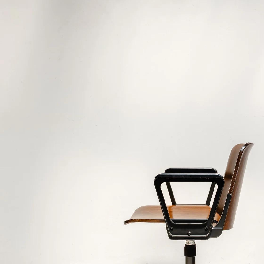 Ein geformter Holzsitz mit einem robusten Metallfuß, der funktionelles Design mit zeitlosem Charakter verbindet. Mit seiner schwenkbaren Funktion und seiner minimalistischen Silhouette ist er eine vielseitige Wahl für moderne Innenräume, vom