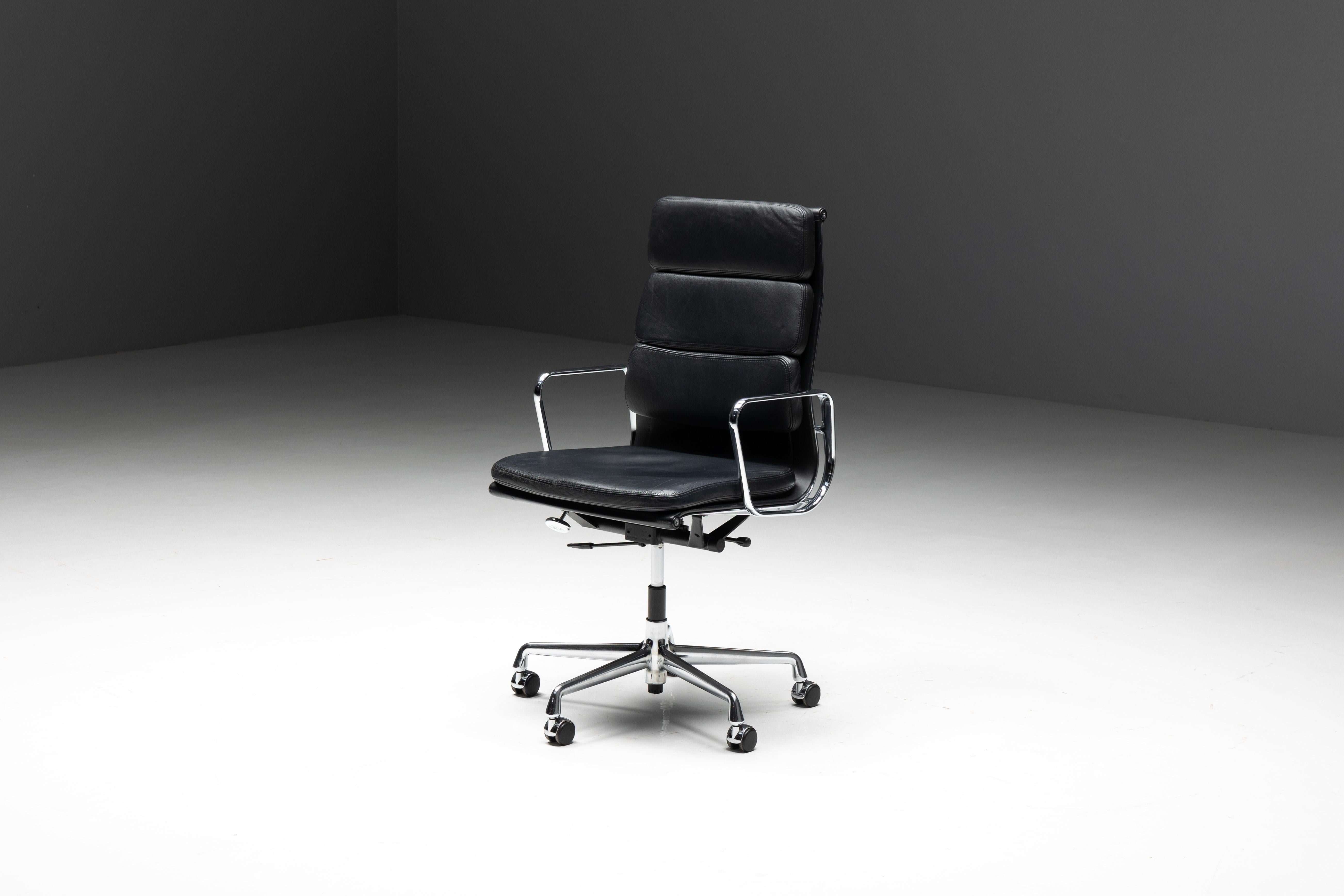 Charles and Ray Eames EA216 softpad office chair, produced by Vitra. This distinguished chair boasts a sleek black leather seat and backrest, complemented by a chrome frame and armrests for a timeless aesthetic. It features swivel, mobile,