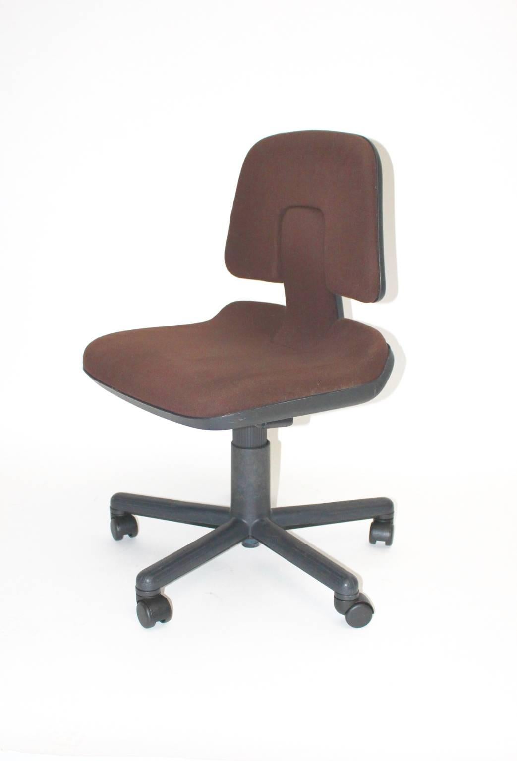 Postmodern vintage office chair designed in 1976 by Wolfgang Mueller Deisig for Vitra. The office chair features a black PVC seat shell with a foam upholstered seat and back and covered with brown textile fabric.
The chair is adjustable from up to