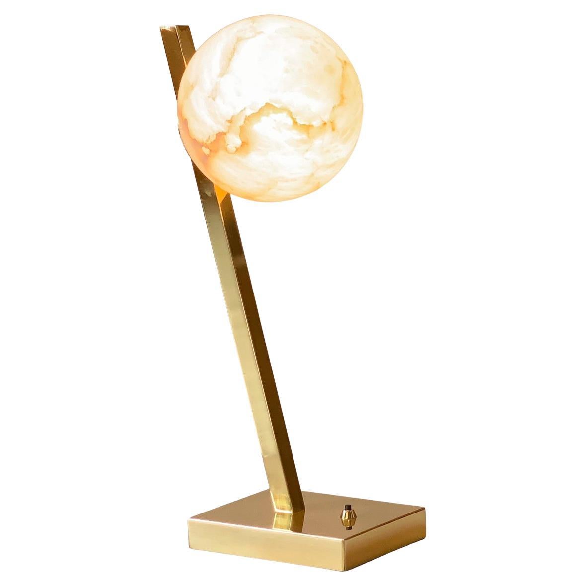 A magnificent tribute to the magical midsummer full moon, this gorgeous table lamp is crafted of elegant brass and exquisite Italian alabaster. Featuring a rectangular brass base, the offset stem showcases a carved sphere made of crystalline