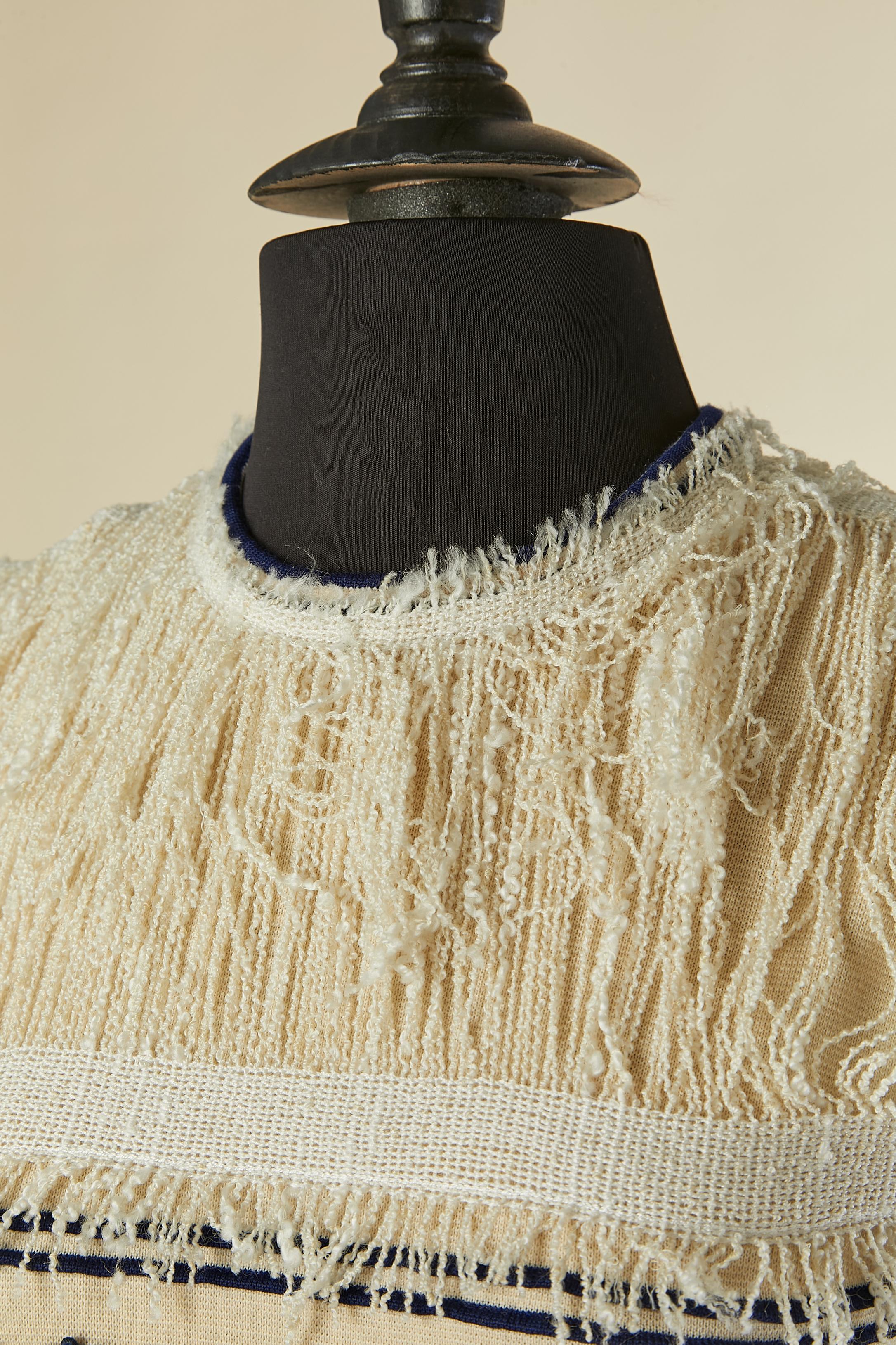 Robe de cocktail sans manches blanc cassé avec franges et appliqué de passementerie de fleurs sur une base de laine. Fermeture à glissière et crochet au milieu du dos. 
TAILLE 36 (Fr) S 