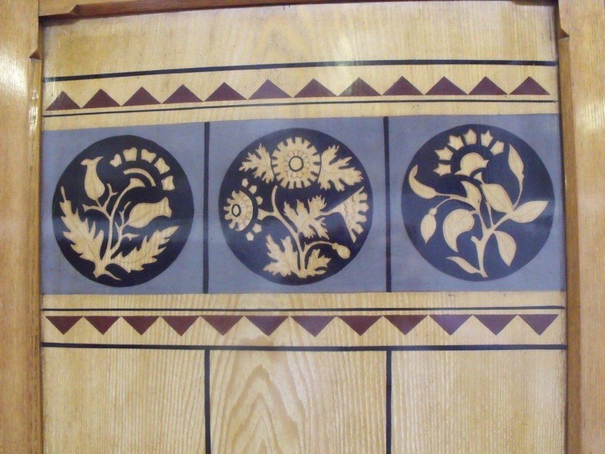 Ogdens of Manchester, in style of Dr C Dresser, 
An Aesthetic Movement three-piece bedroom suite made from Ash with intricate stylized fruitwood floral inlays to each piece.
Consisting of a treble wardrobe opening to reveal three large upper open