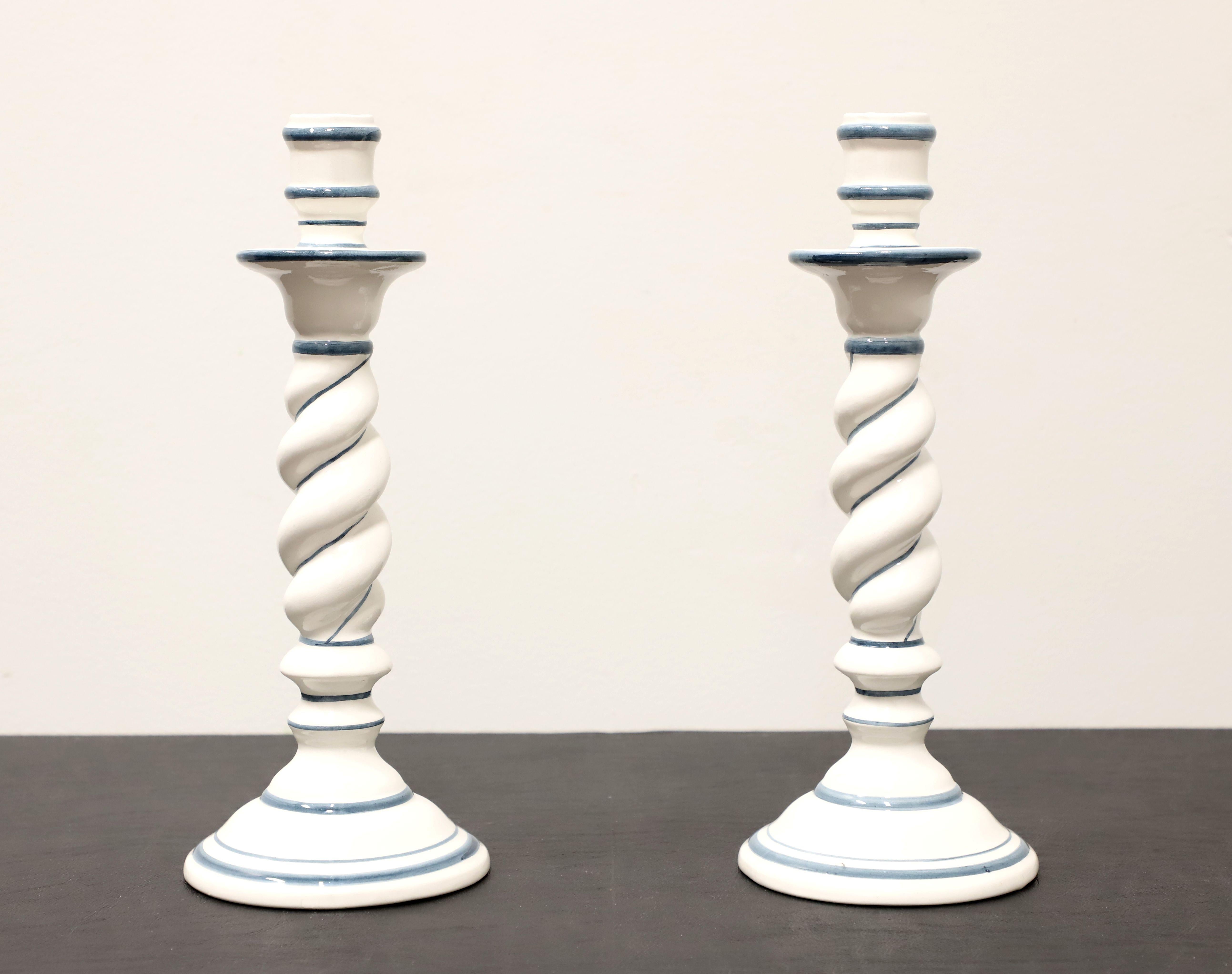 Ein Paar italienische Kerzenleuchter im zeitgenössischen Stil von OGG. Handbemalte Keramik in weißer und marineblauer Farbe mit einer säulenartigen Form und ausgeprägter Drehung. Hergestellt in Italien, Mitte des 20. Jahrhunderts. 

Maße: 4.5w 4.5d
