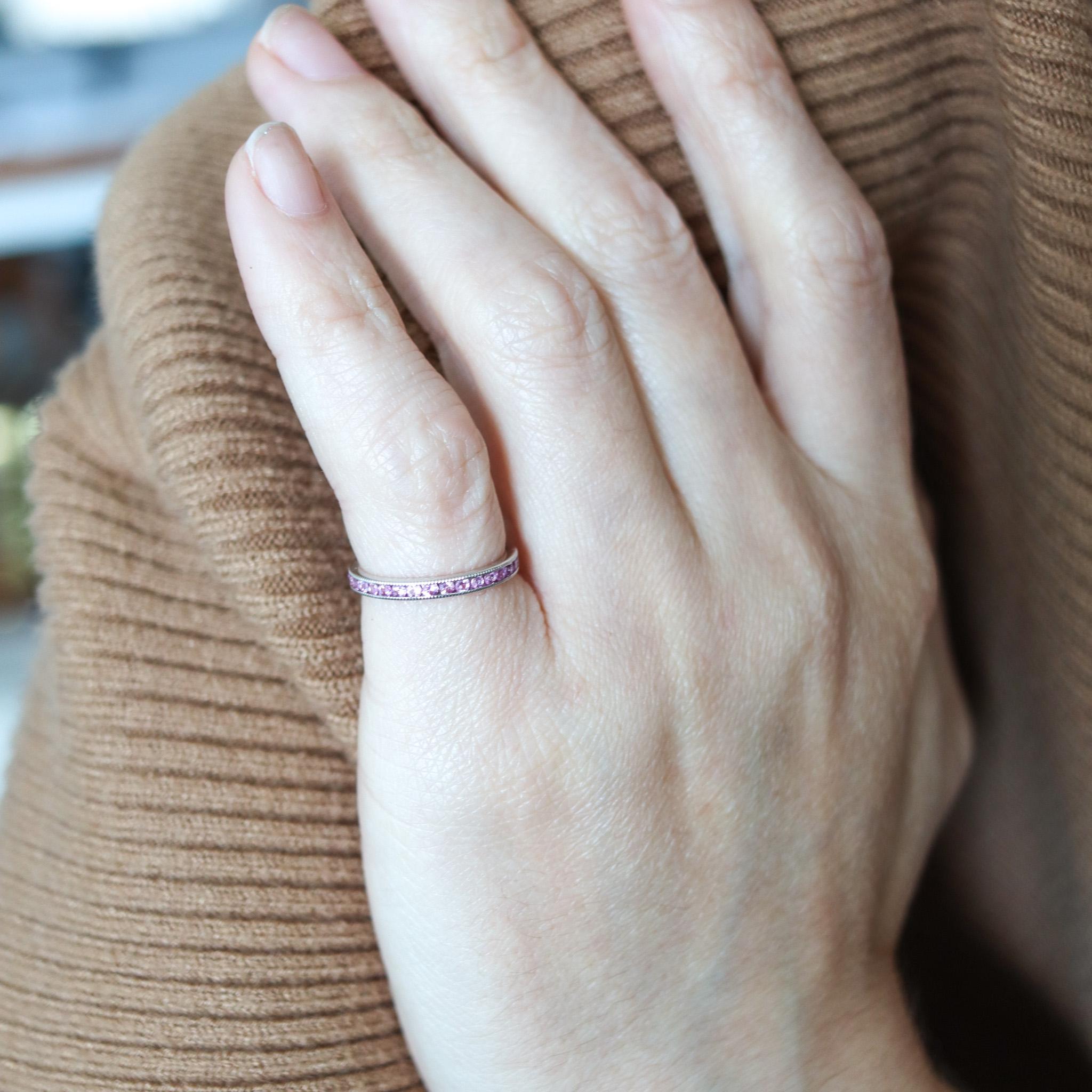 An eternity ring band with natural pink sapphires.

Contemporary eternity band ring crafted in America in solid white gold of 18 karats with high polished finish. It is mounted in a plain channel setting with 35 calibrated round brilliant cuts of